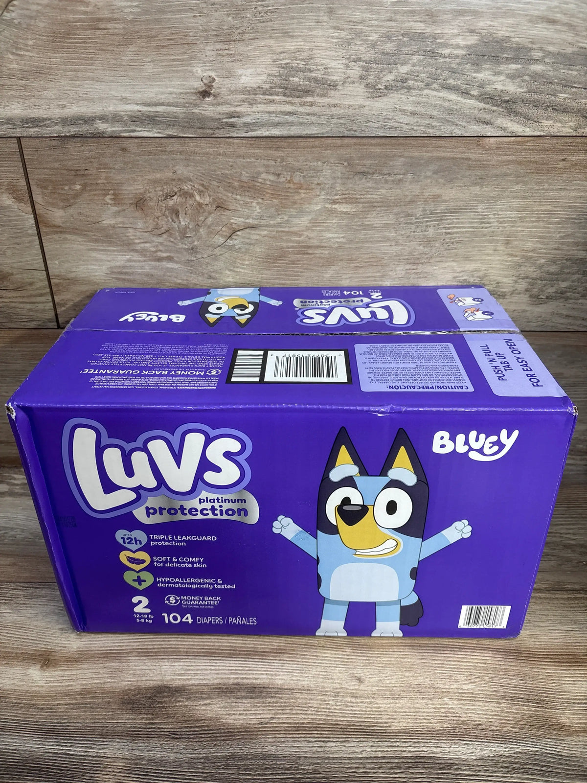 Front view of Luvs Platinum Protection size 2 box, 104 count, showing Bluey character on purple packaging on wood background