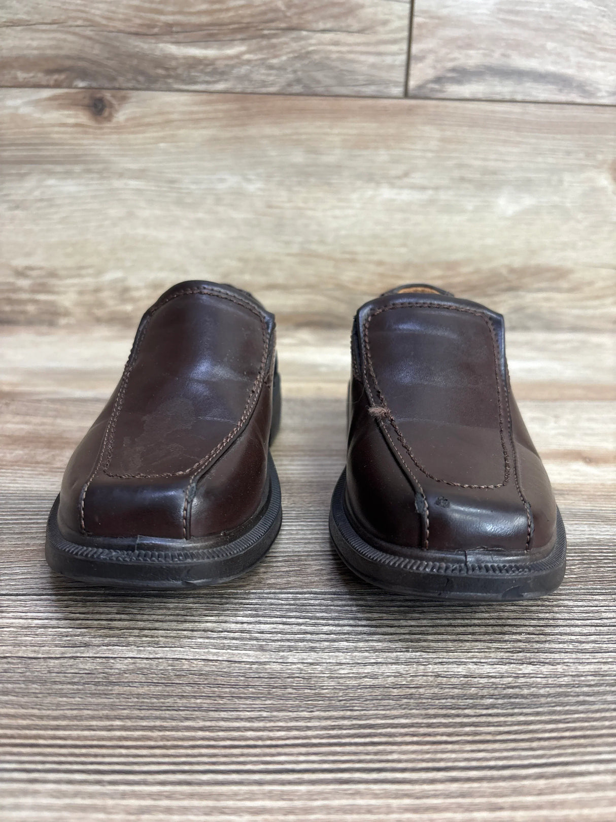 Pair of dark brown toddler leather slip-on shoes on wooden floor for kids resale