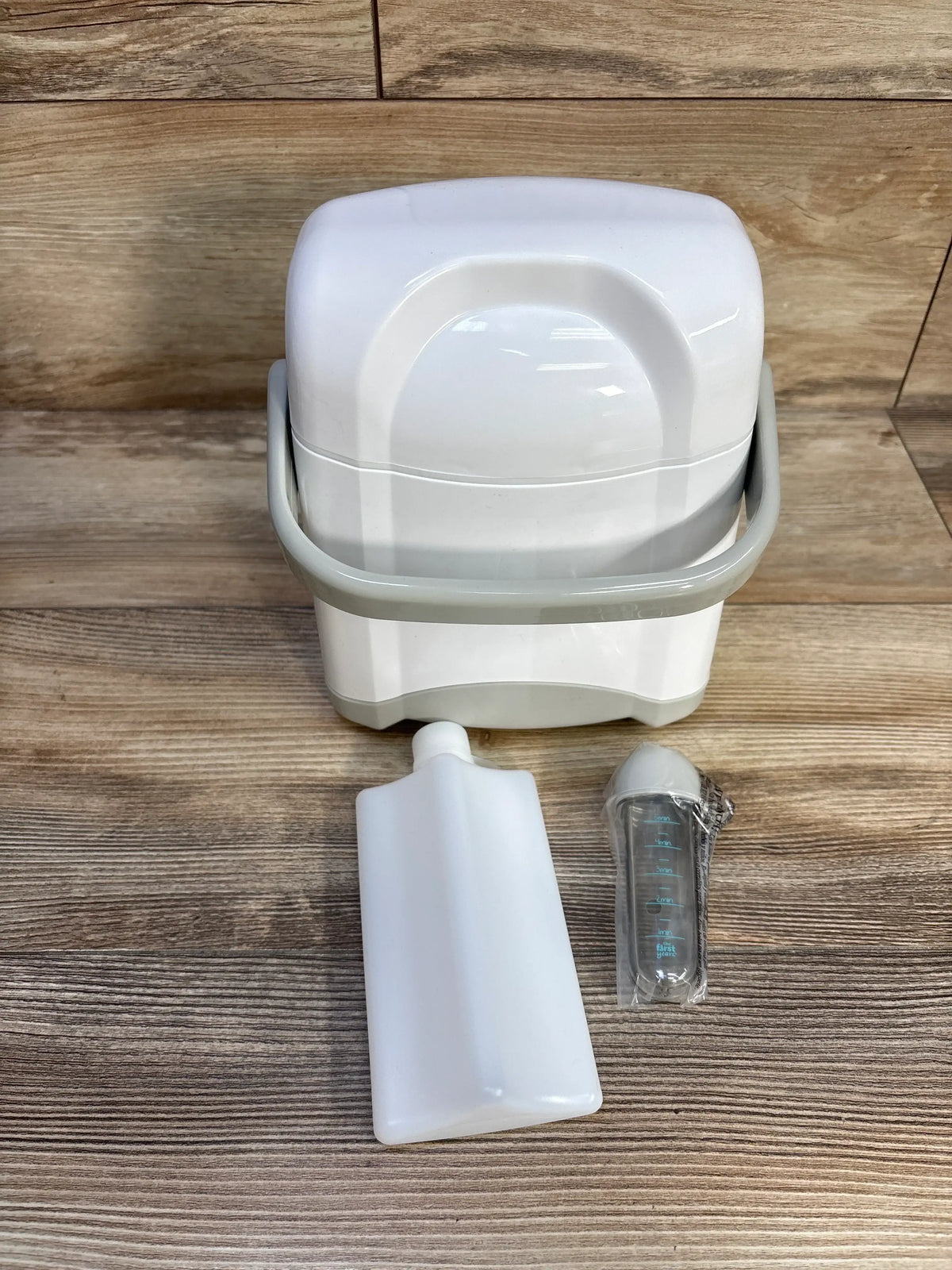 Front view of The First Years Bottle Cooler showcasing its removable ice pack and bottle on a wood grain surface