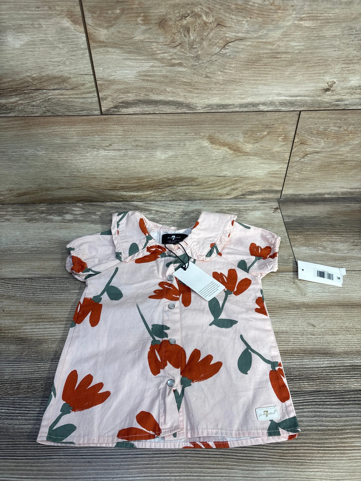 Front view of 7 For All Mankind floral button-up shirt showcasing pink cotton fabric, collar, buttons, and wood-look flooring