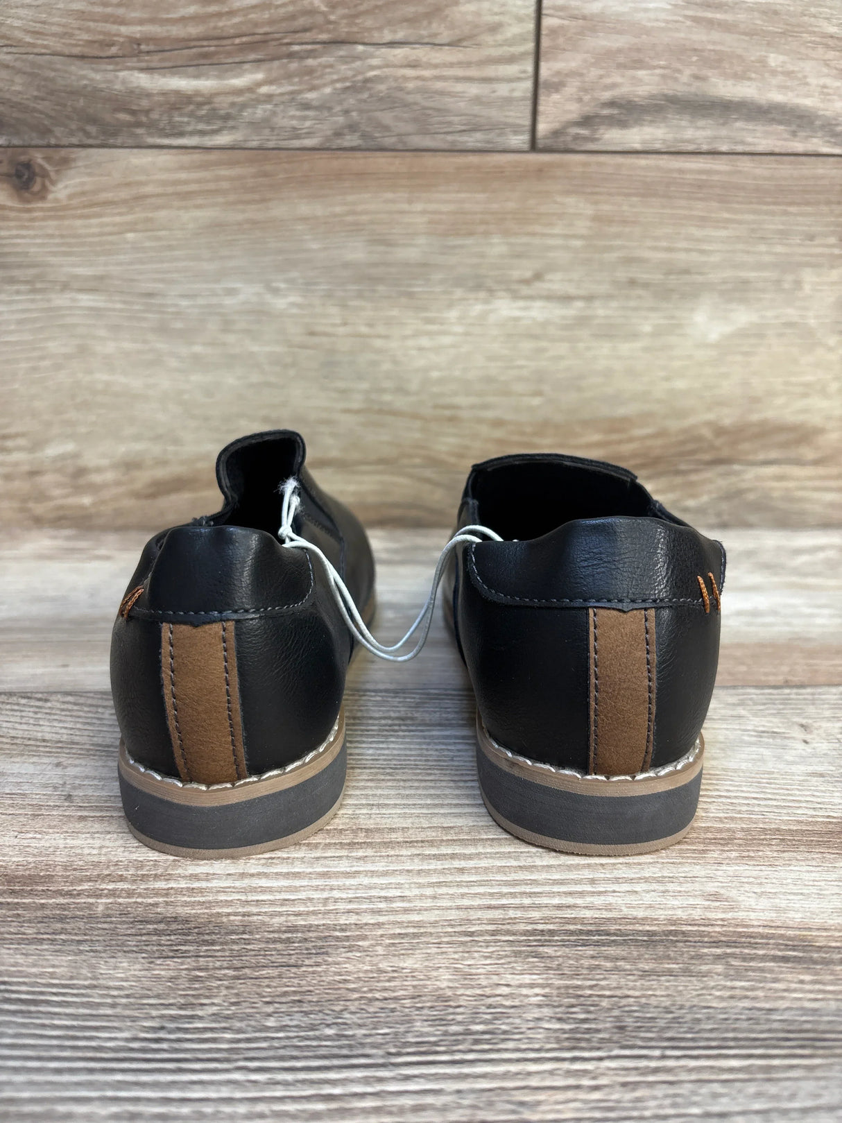 Back view of black and brown kids dress shoes on wooden floor