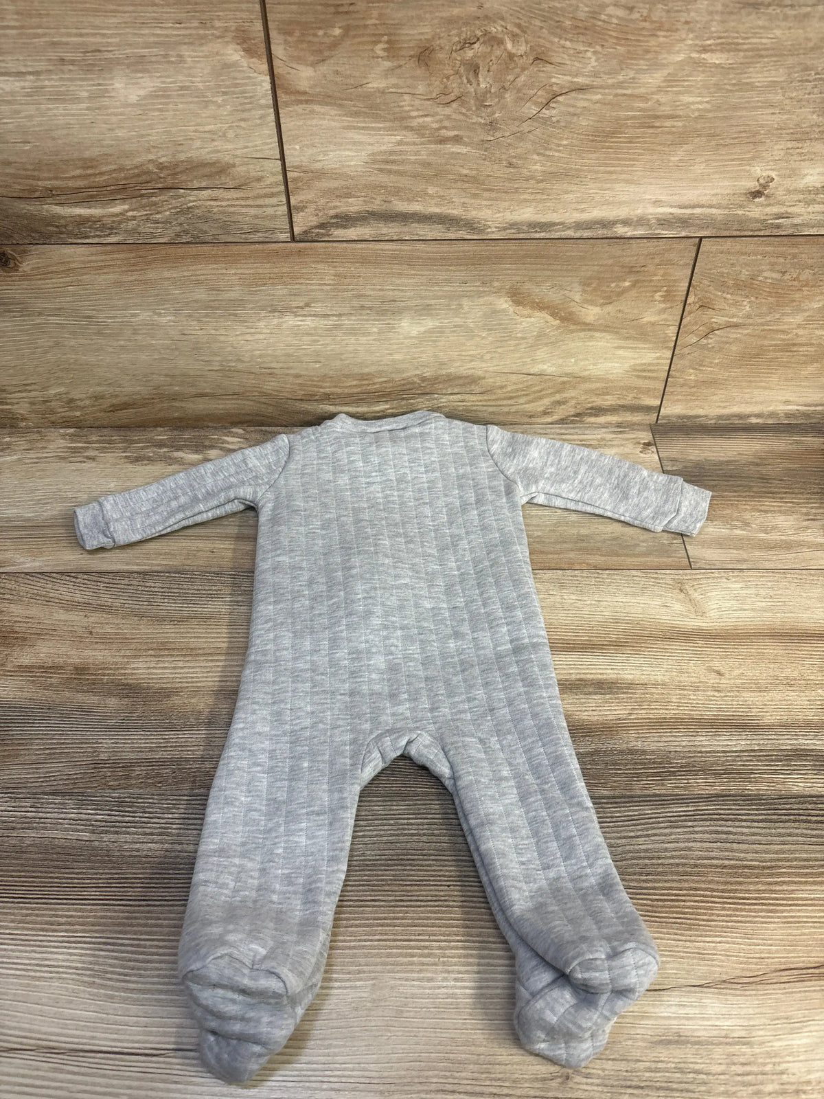Top view of Kyle + Deena Quilted Cutie Sleeper in grey, showcasing quilted texture and enclosed feet on a wood floor