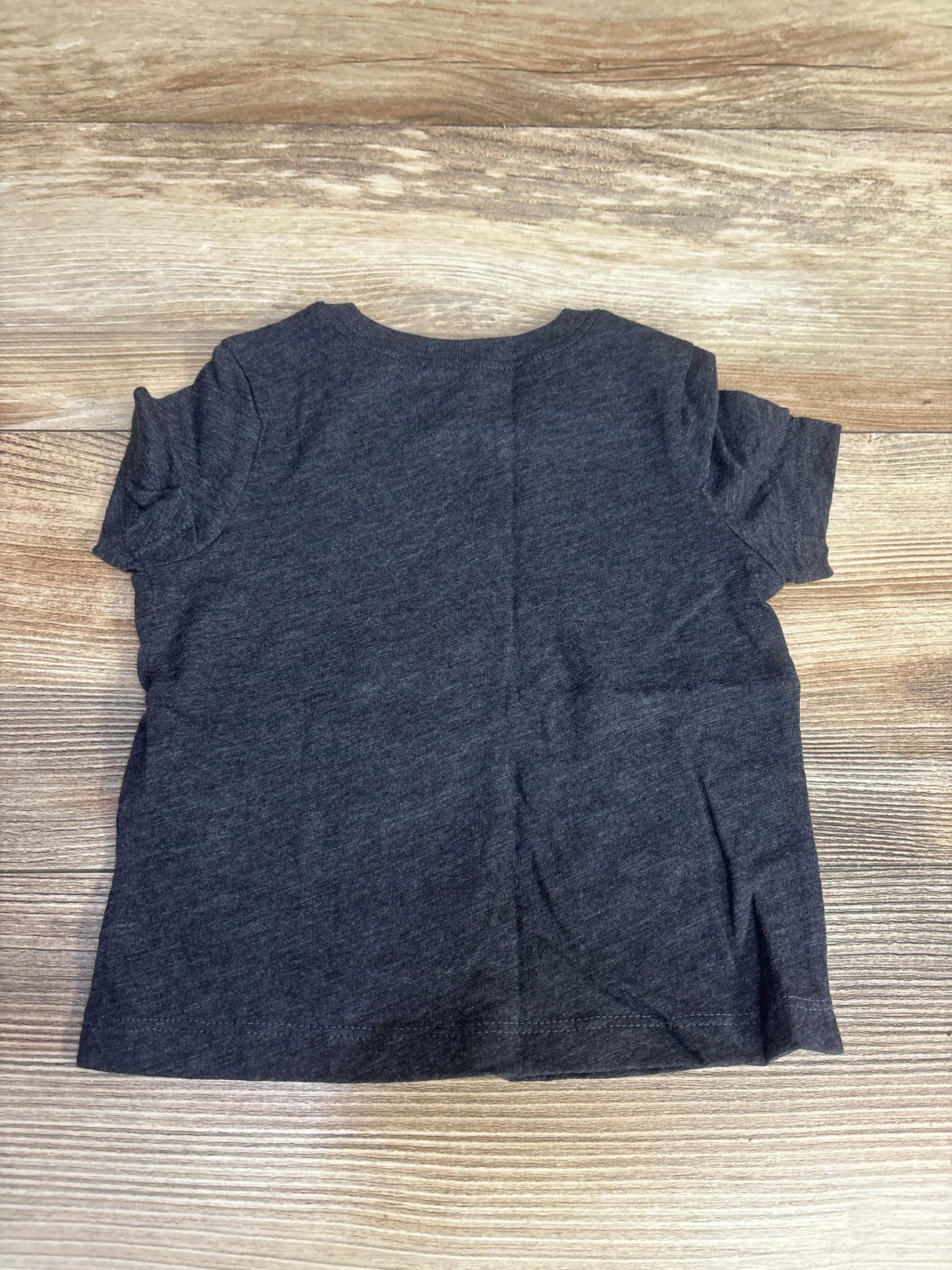 Dark gray short-sleeve t-shirt laid flat on wooden surface