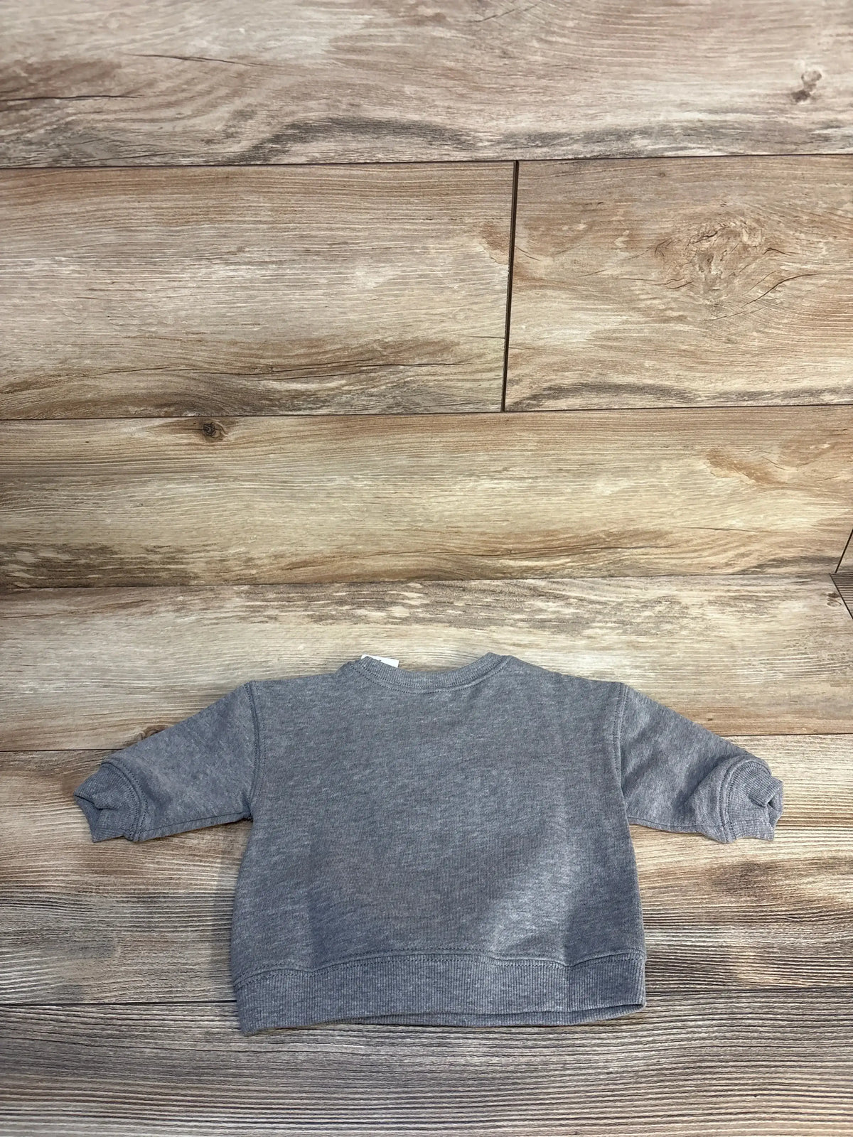 Gray long sleeve toddler sweatshirt on wooden background, gently used kids clothing