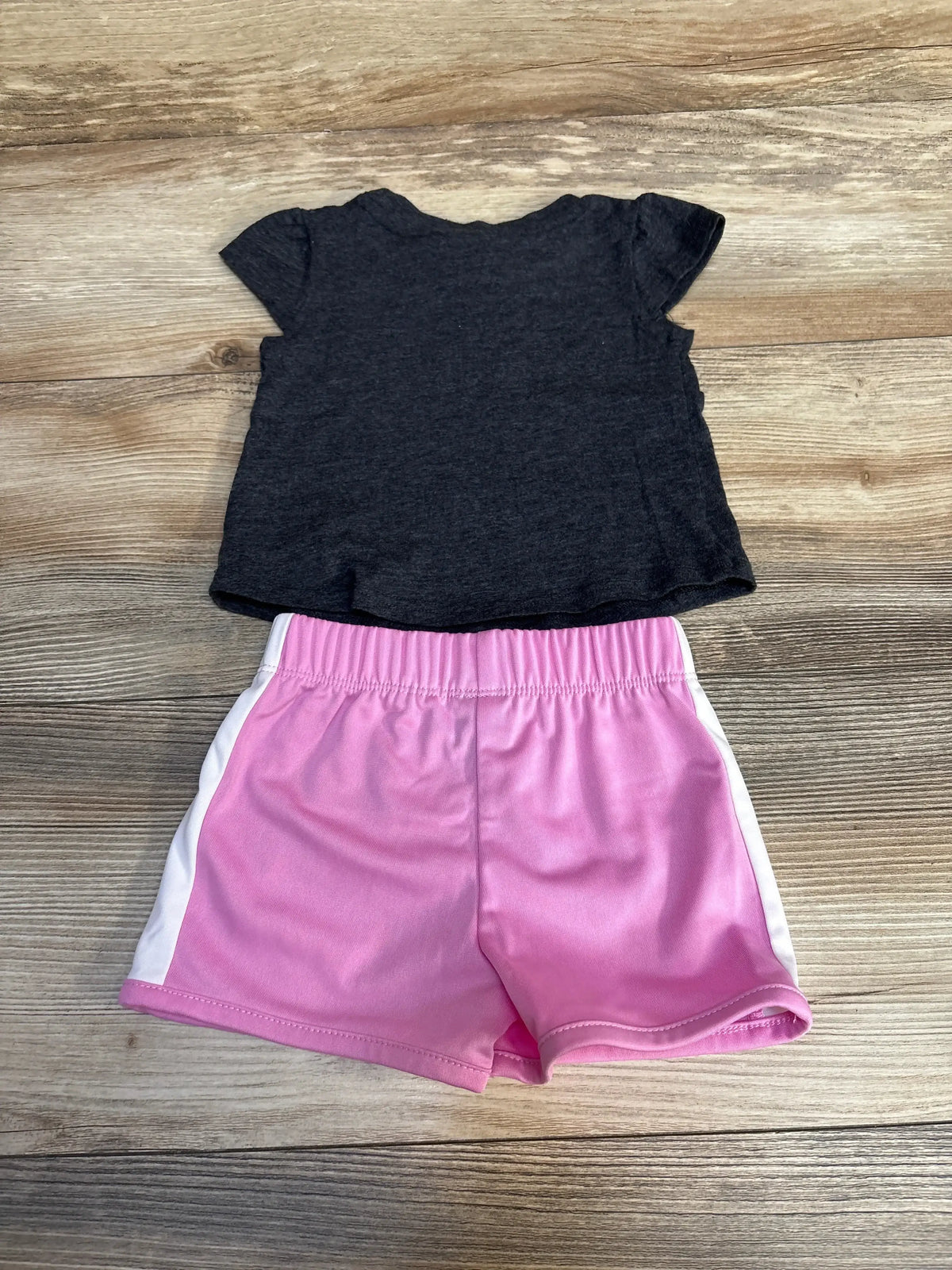 Girls dark grey short sleeve shirt and pink athletic shorts set on wooden background
