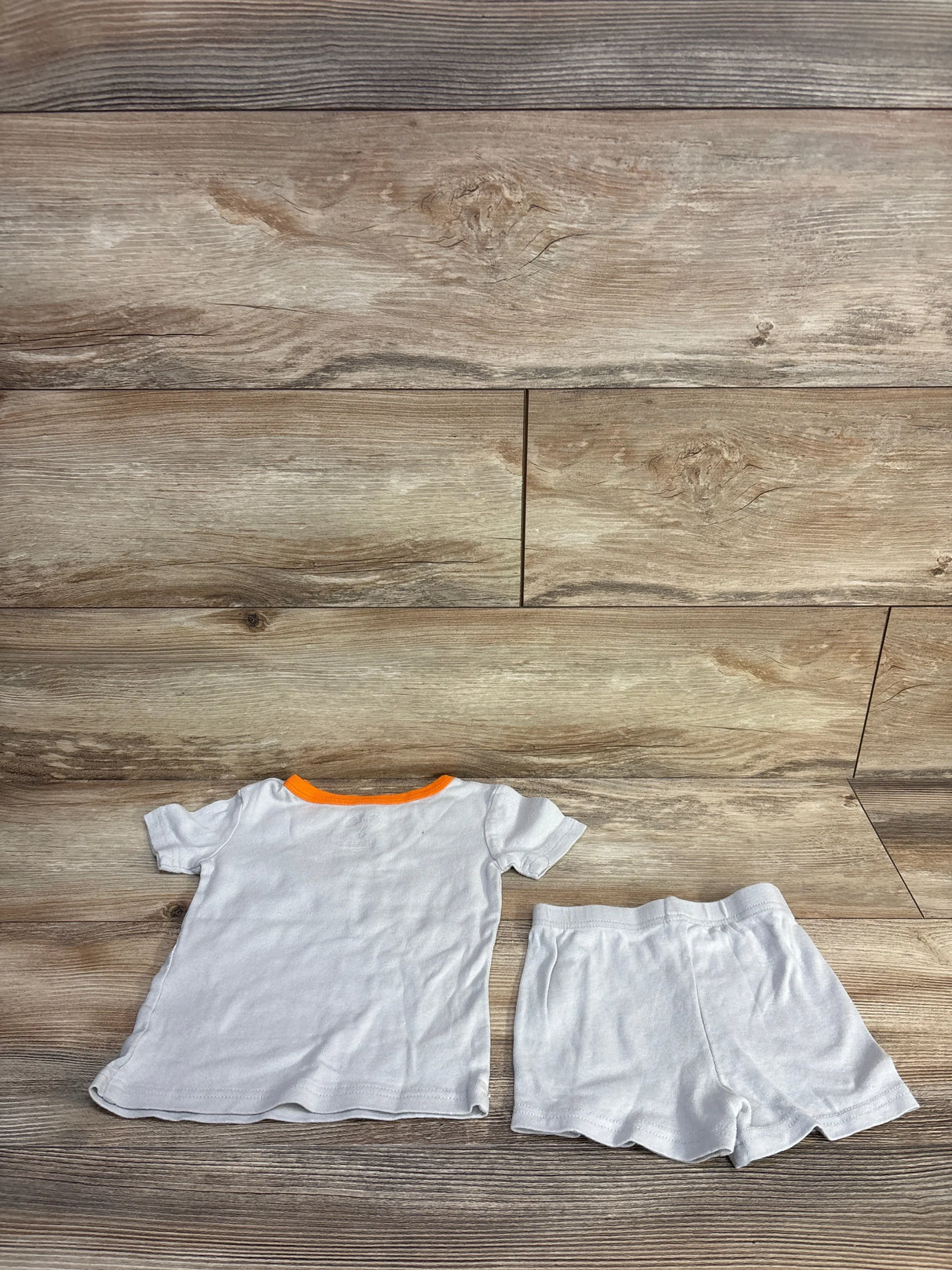 Flat lay of 2-piece TMNT pajama set, back of white top with orange neck trim and matching shorts, size 4T