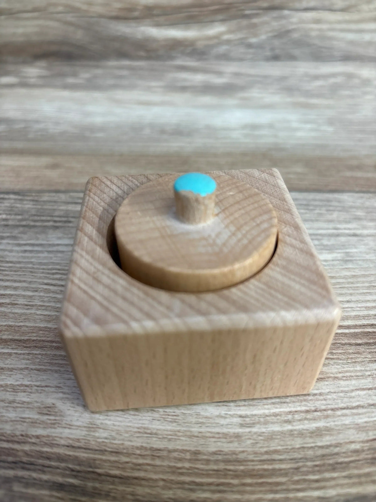 Wooden Montessori toy with blue knob on square base for toddler fine motor skills