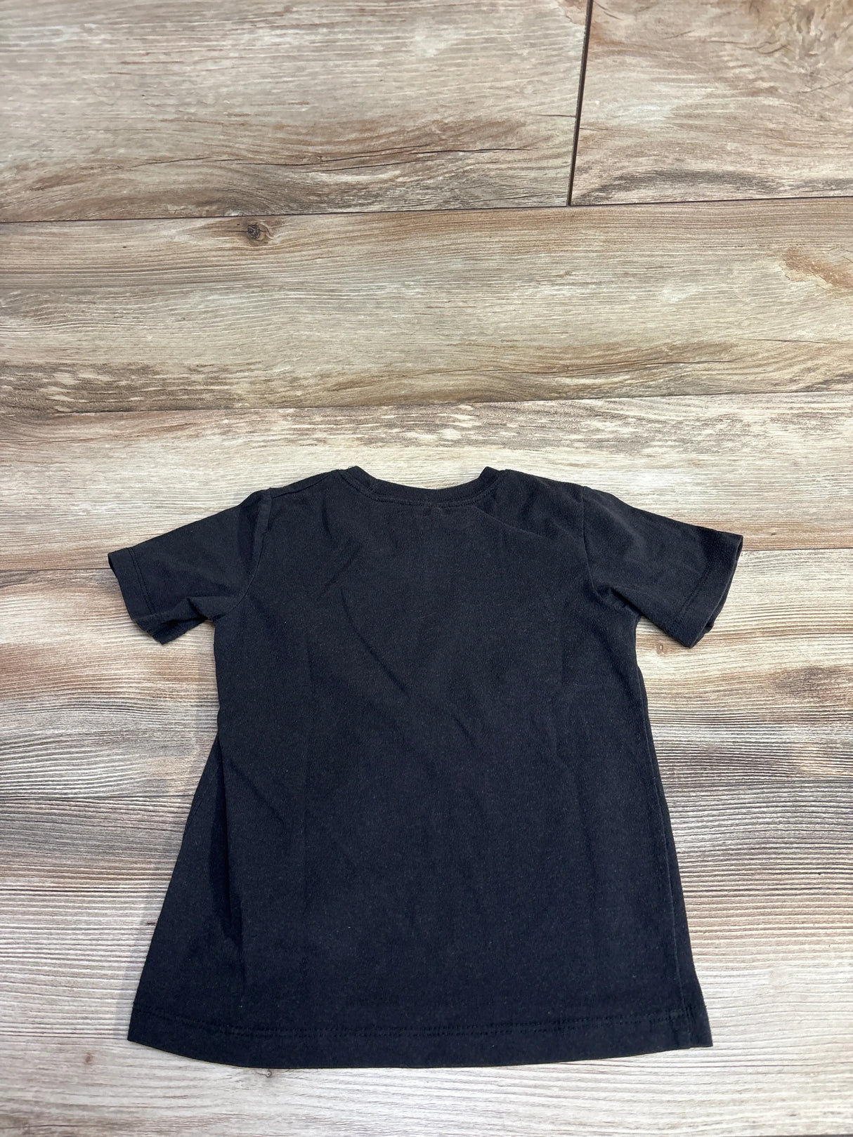 Back view of The Notorious B.I.G. toddler T-shirt size 5T showcasing plain black short sleeves on light wood floor background