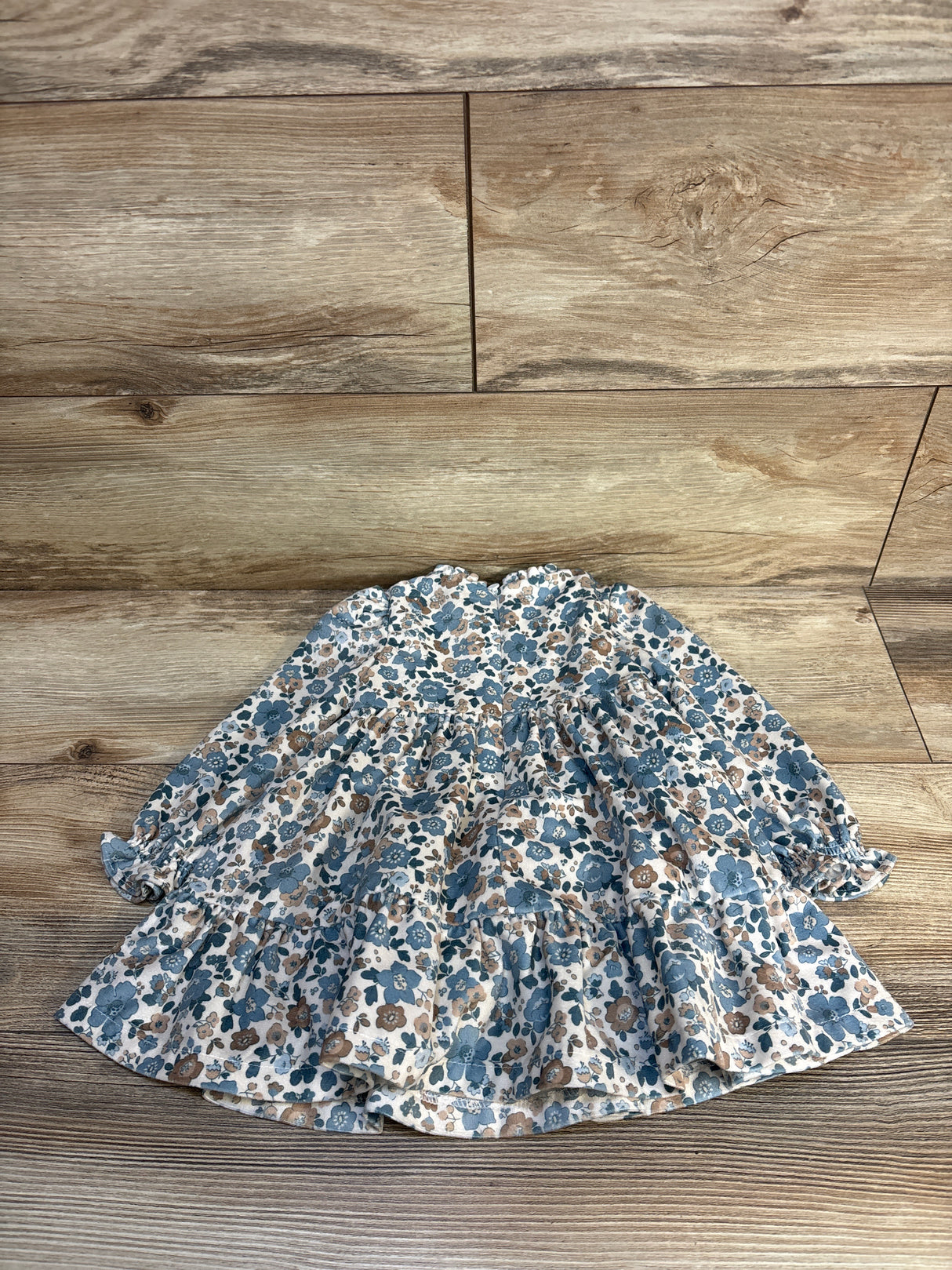 Flat lay of Mayoral ruffled velvet baby dress, floral ivory, size 12 months, showcasing ruffled tiers and long sleeves on wood floor