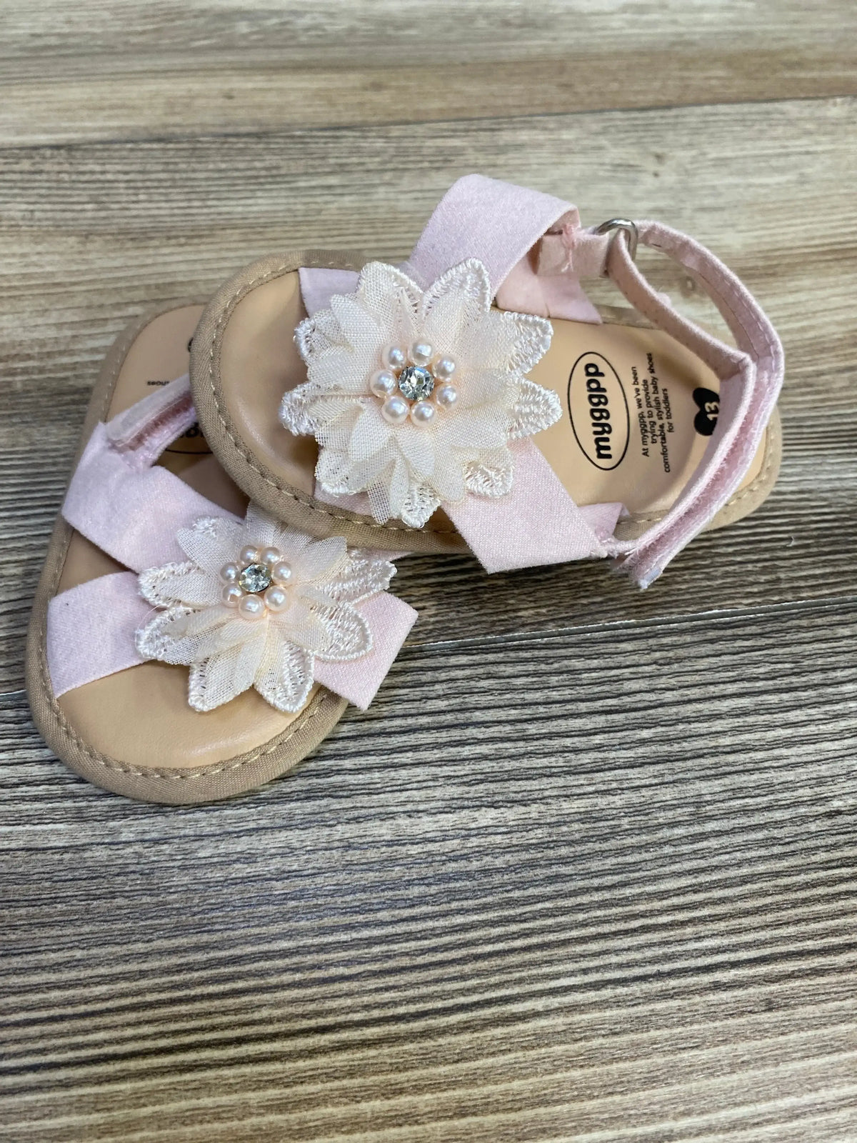 Front view of pink cross-strap toddler sandals showcasing pearl embellishments with white background