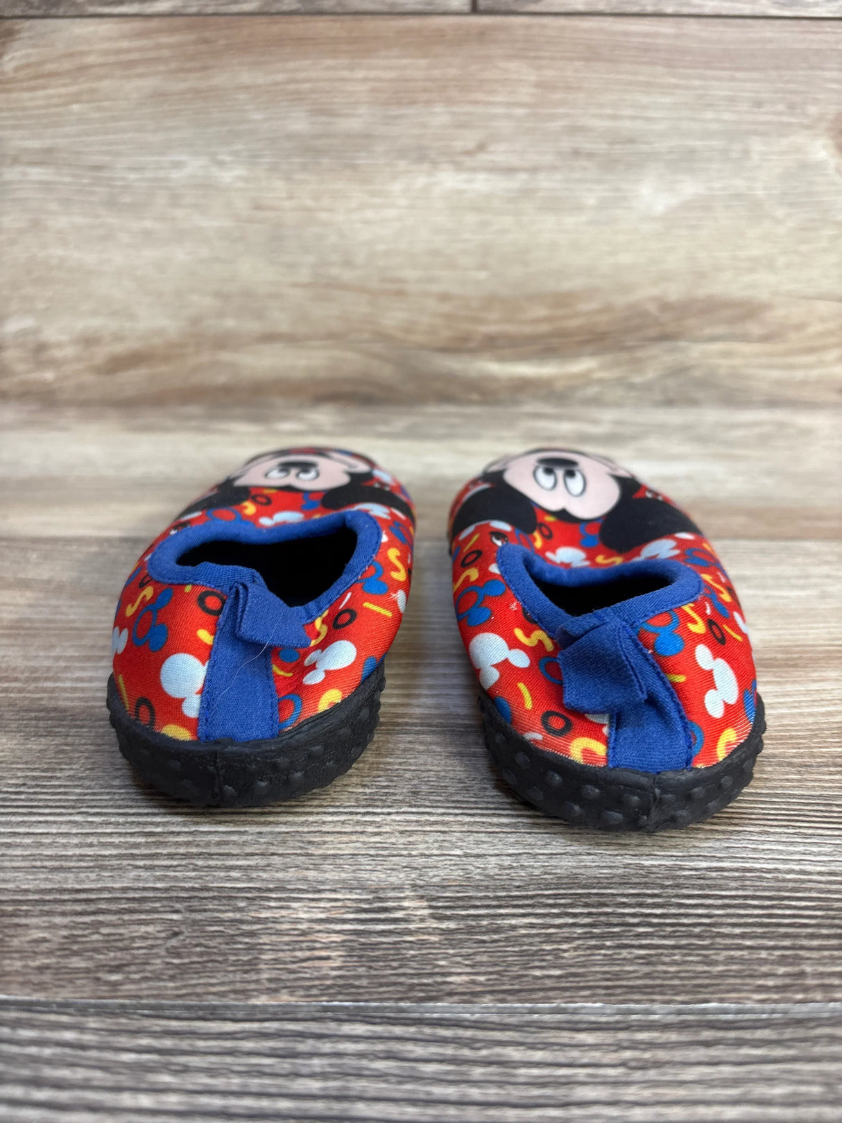 Mickey Mouse toddler shoes with red pattern and blue accents on wooden floor