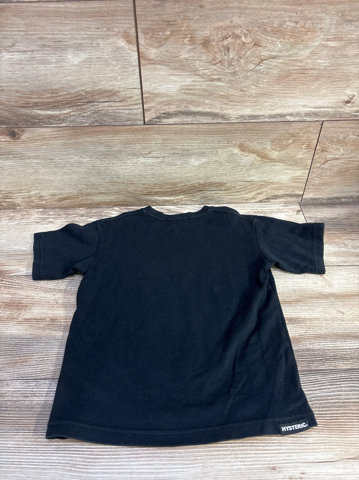 Black Hysteric Glamour Mini Vintage Shirt, size 4T, back view with short sleeves and HYSTERIC hem label on wood-look floor