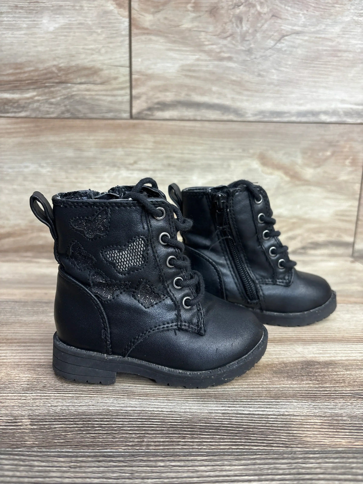 Three-quarter view of Sugar faux leather butterfly toddler boots size 5C showcasing butterfly embroidery and side zipper on wooden floor