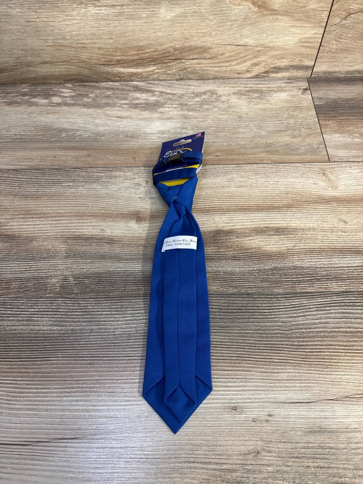 Front view of Ee Dee solid royal blue clip-on tie showcasing the clip fastening on a wood-grain floor