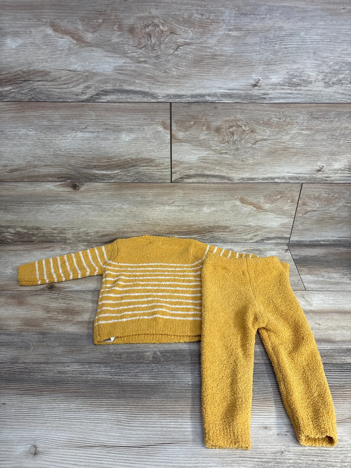Yellow striped toddler sweater and pants set on wood background, kids clothing