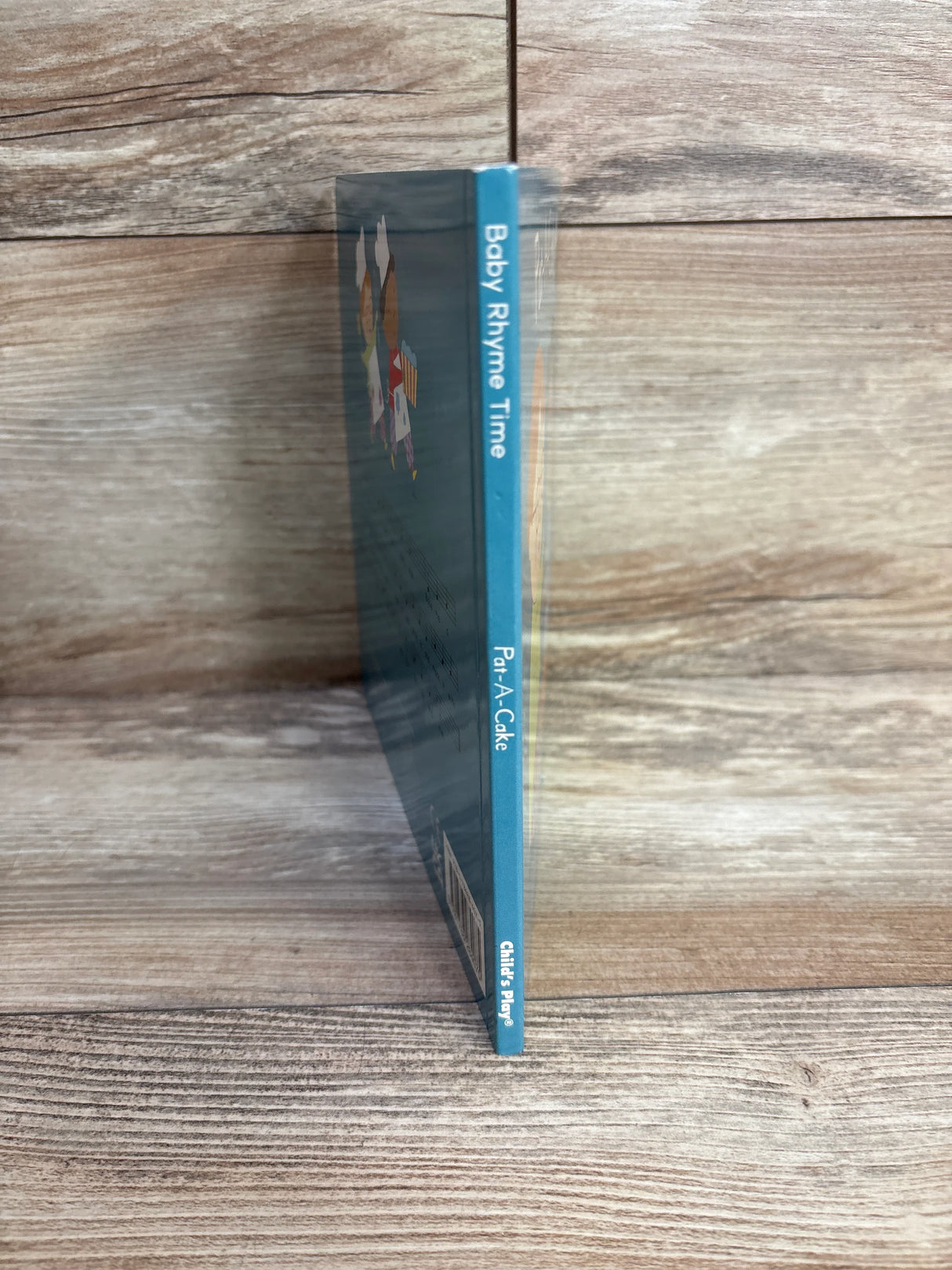 Baby Rhyme Time Pat-A-Cake board book spine on wood background, Child's Play