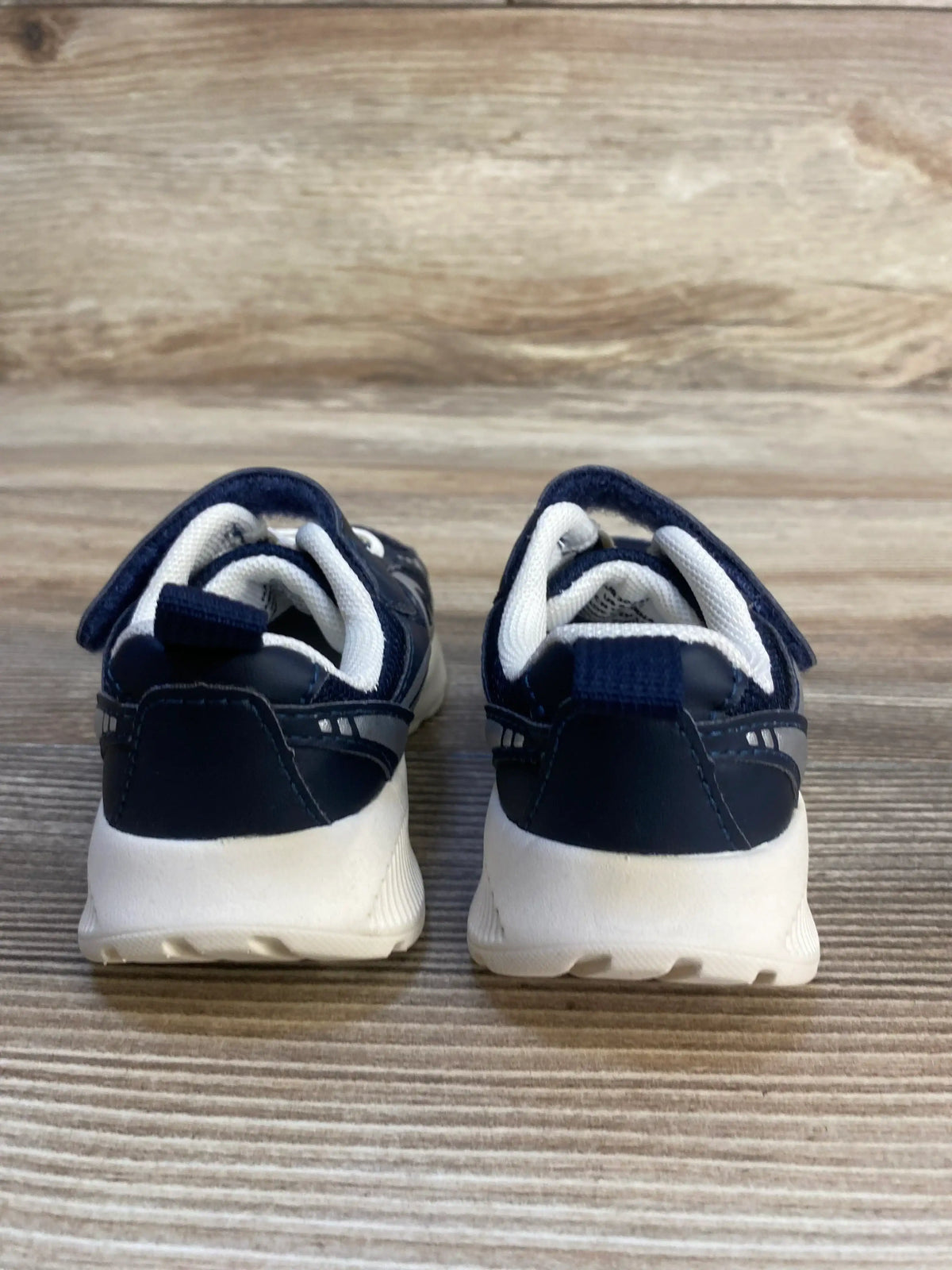 Navy blue and white toddler sneakers with velcro straps on wood background