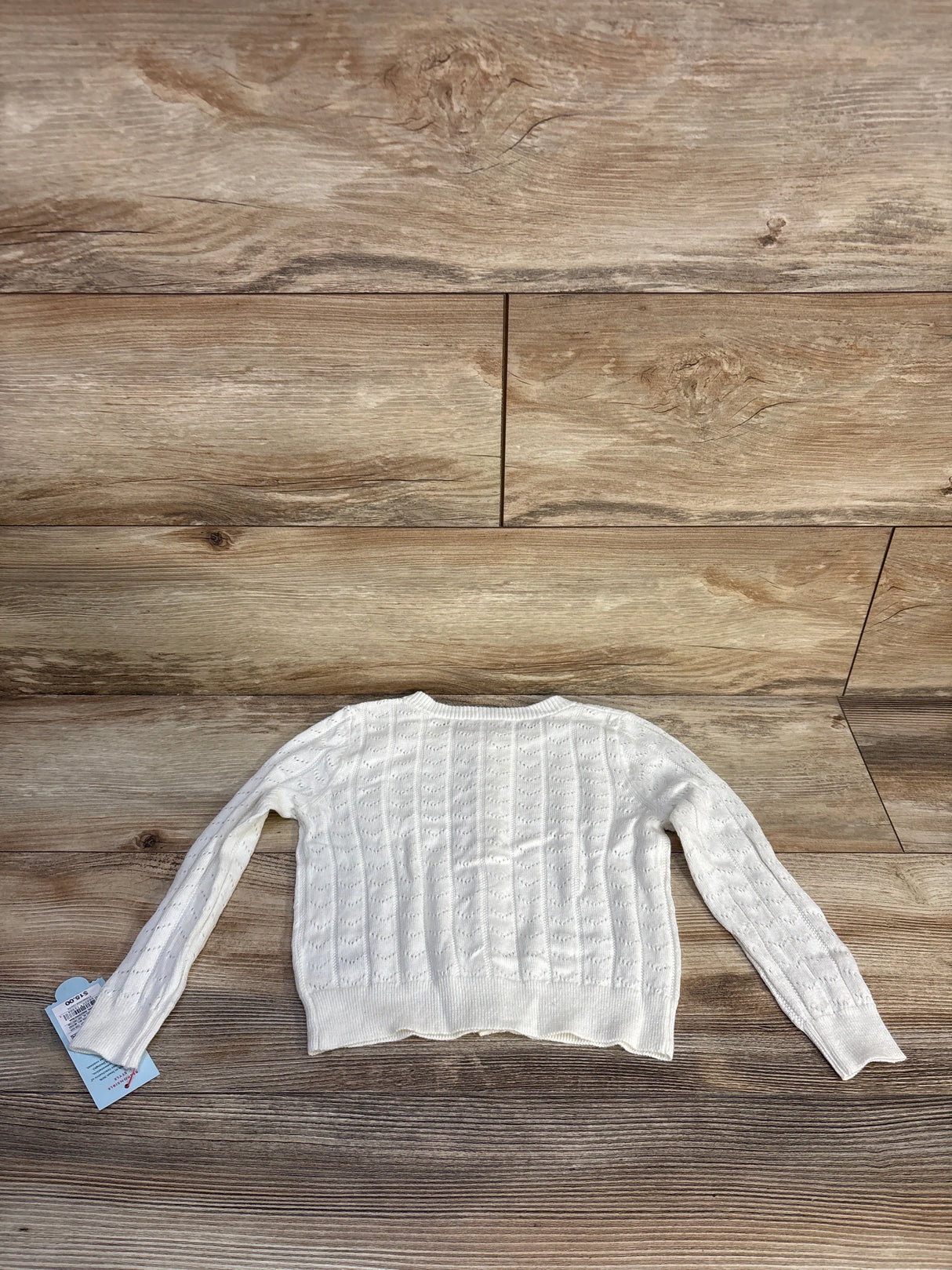 Flat lay of white Cat and Jack toddler cardigan 2T showing pointelle knit and scalloped hem on wood background