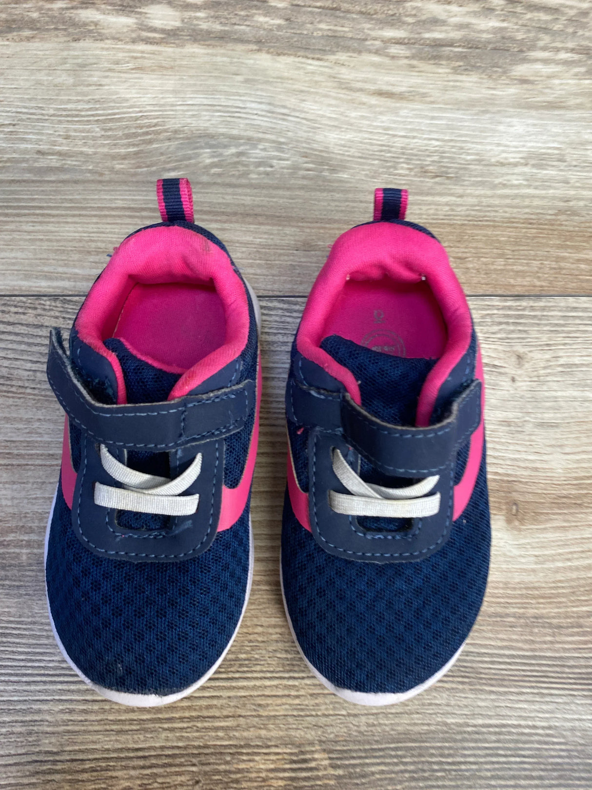 Top view of Wonder Nation jogger sneakers in navy and pink showing Velcro strap and elastic laces on wood floor