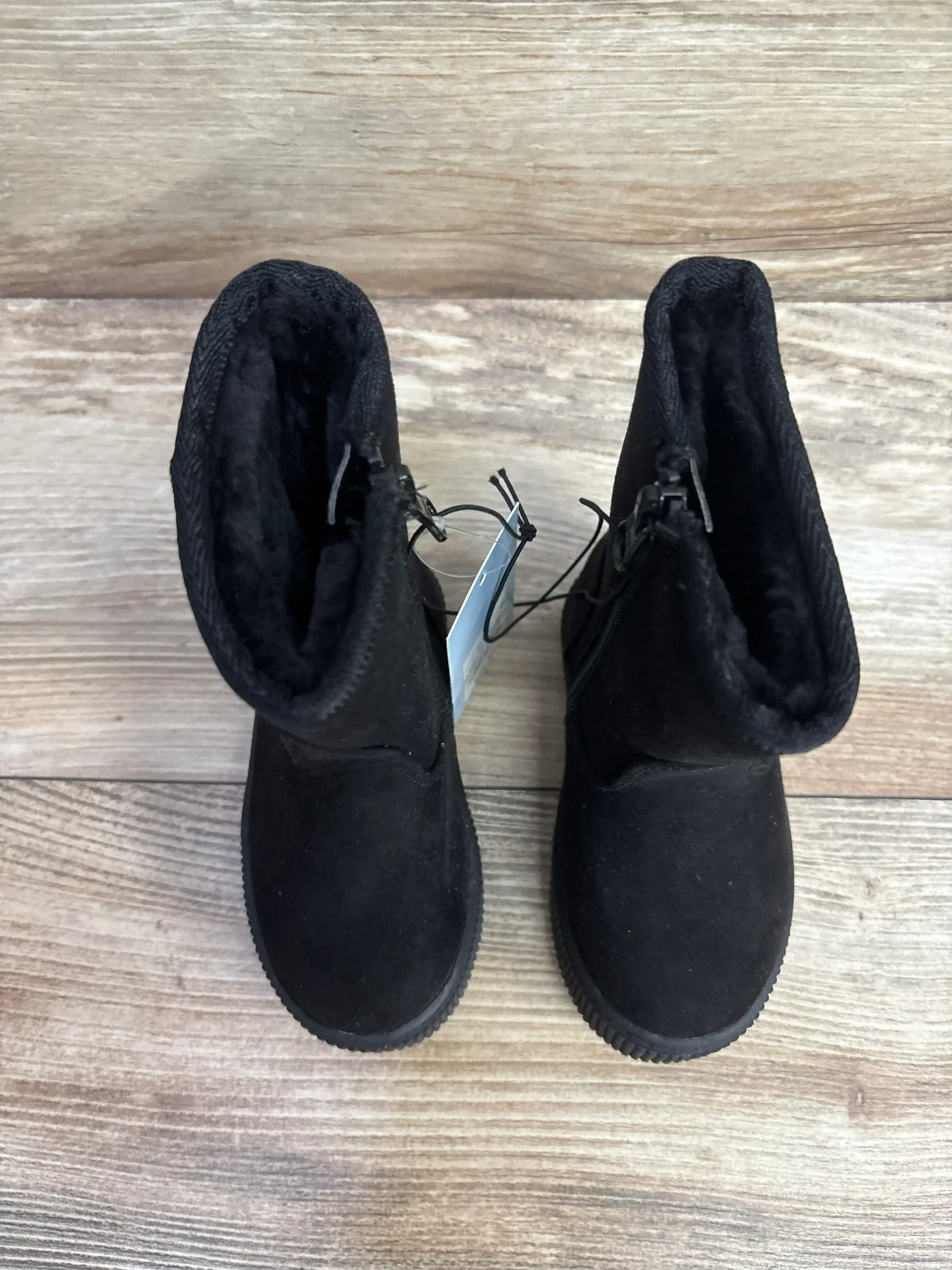 Black suede kids boots with plush lining on wooden floor