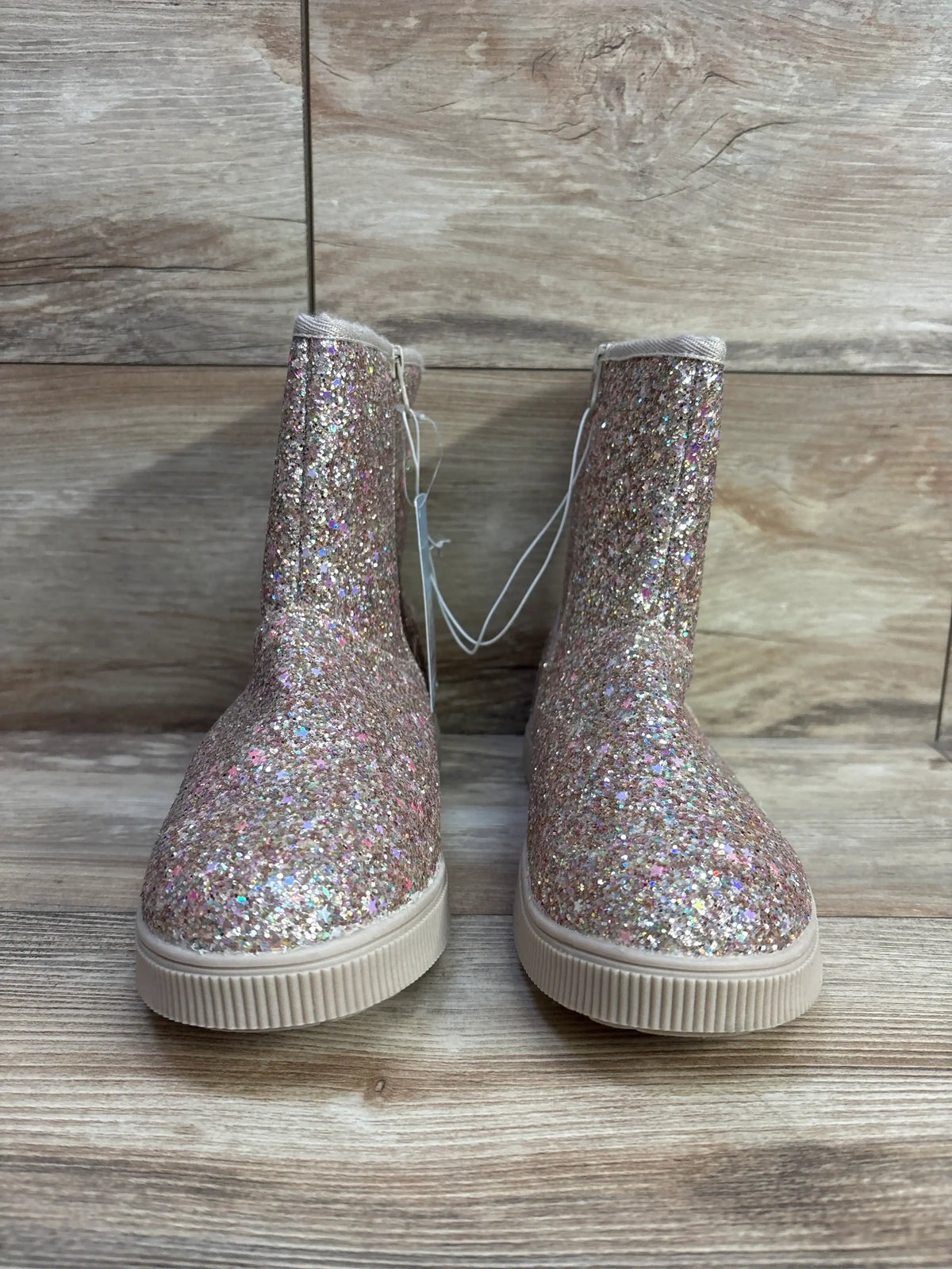 Front view of Cat and Jack kids glitter ankle boots with multicolor glitter upper, cream sole and side zip on wood background