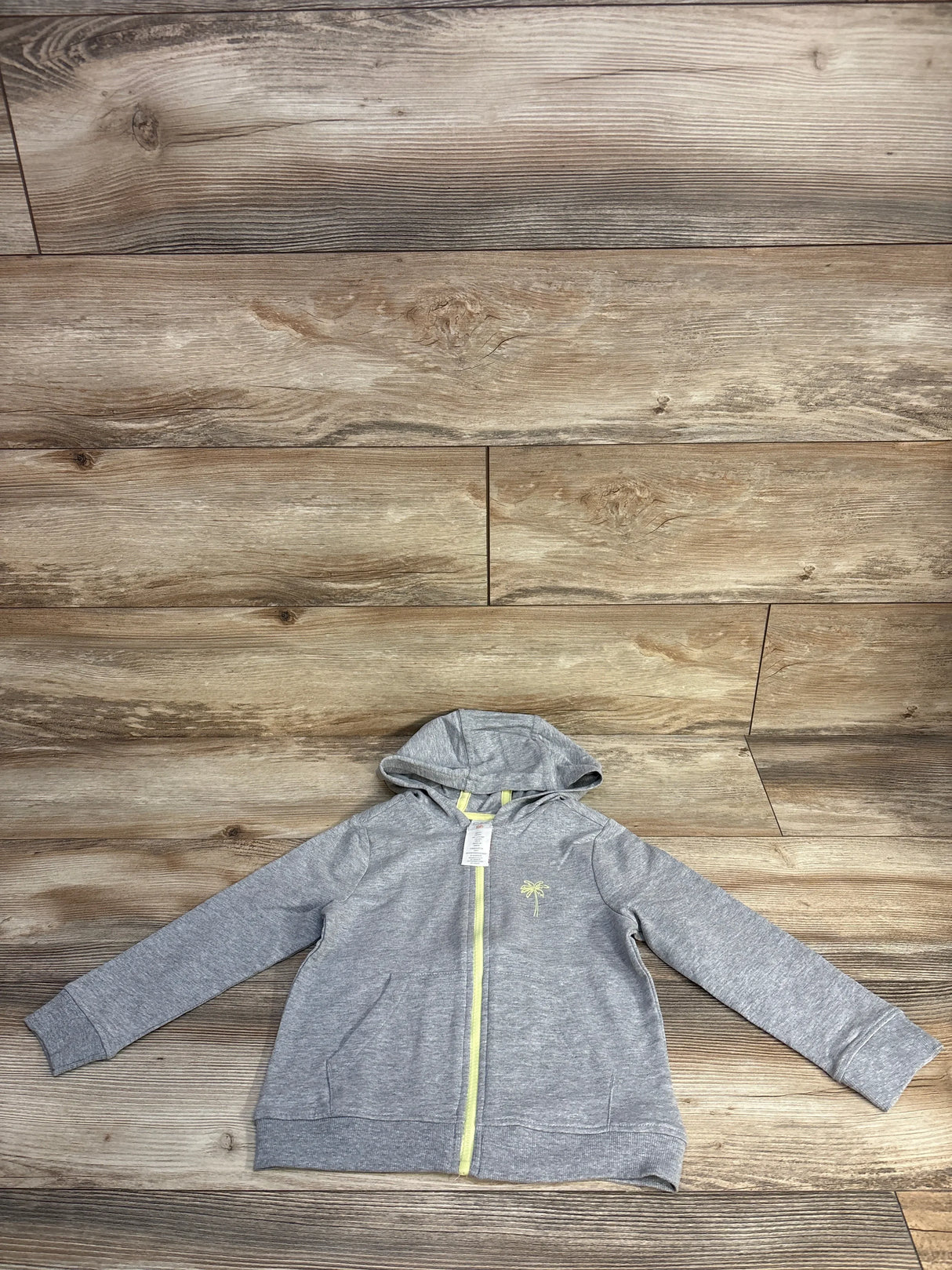 Gray zip-up hoodie with yellow trim on wood floor background