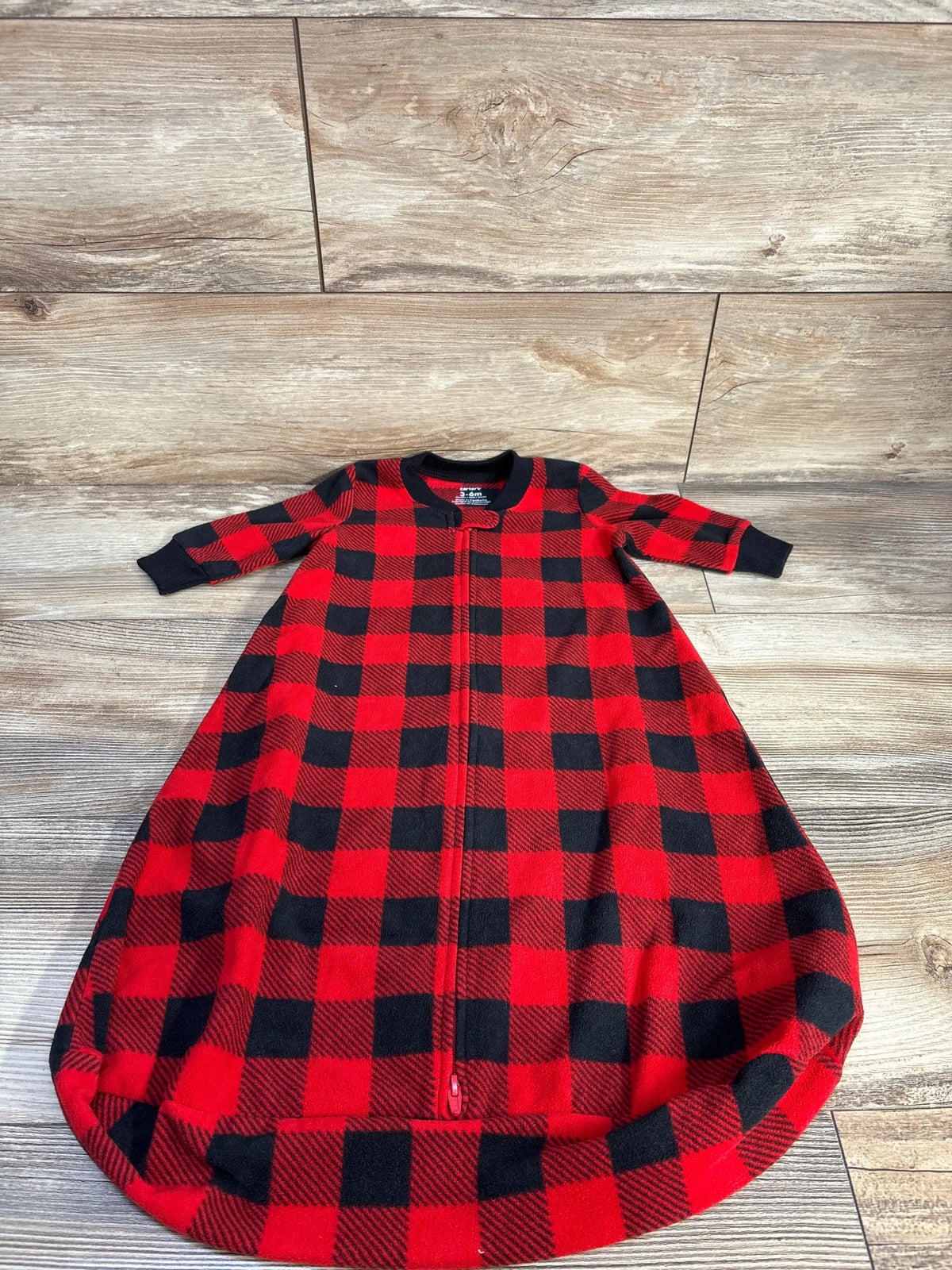Front view of Carter’s red plaid sleep sack showcasing the full-length two-way zipper on a wood floor