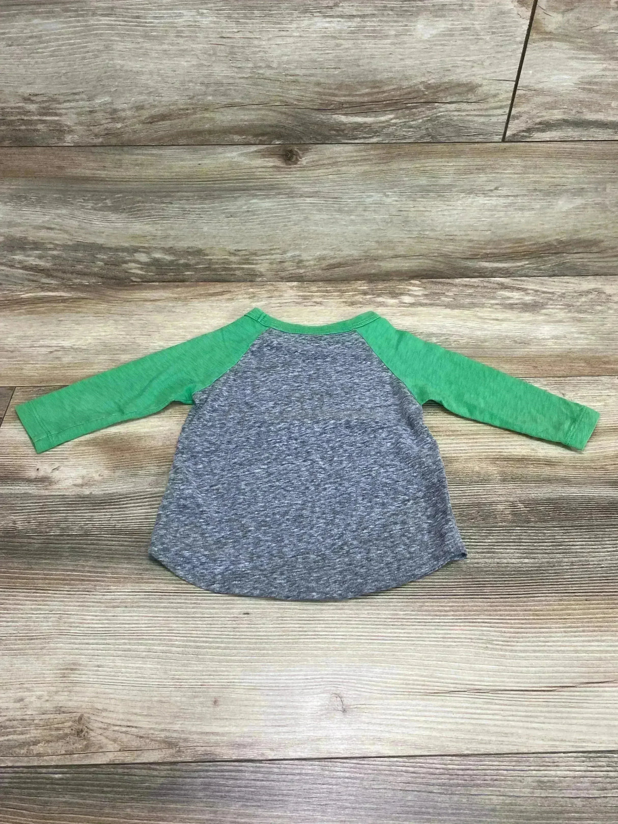 Back view of toddler raglan shirt showcasing green raglan sleeves and heather gray body, size 2T, laid flat on wood background