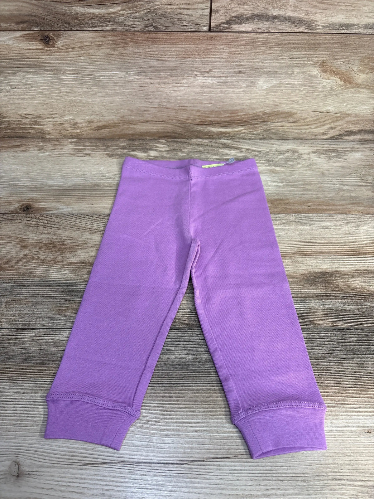 Purple toddler cotton pants with cuffed ankles on wooden floor background