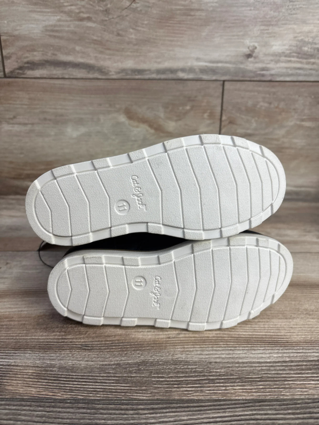 Bottom view of Cat & Jack kids' shoes with white rubber soles, size 11, on wood floor