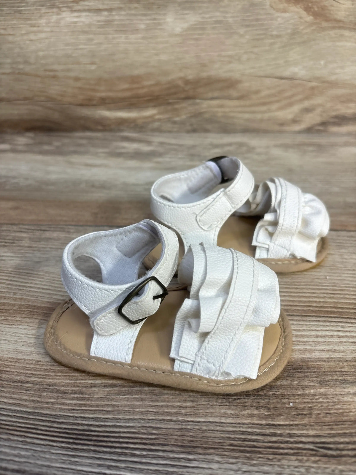 Front view of Muchenggift white bowknot soft sole sandals showcasing adjustable ankle straps on a wood-grain background