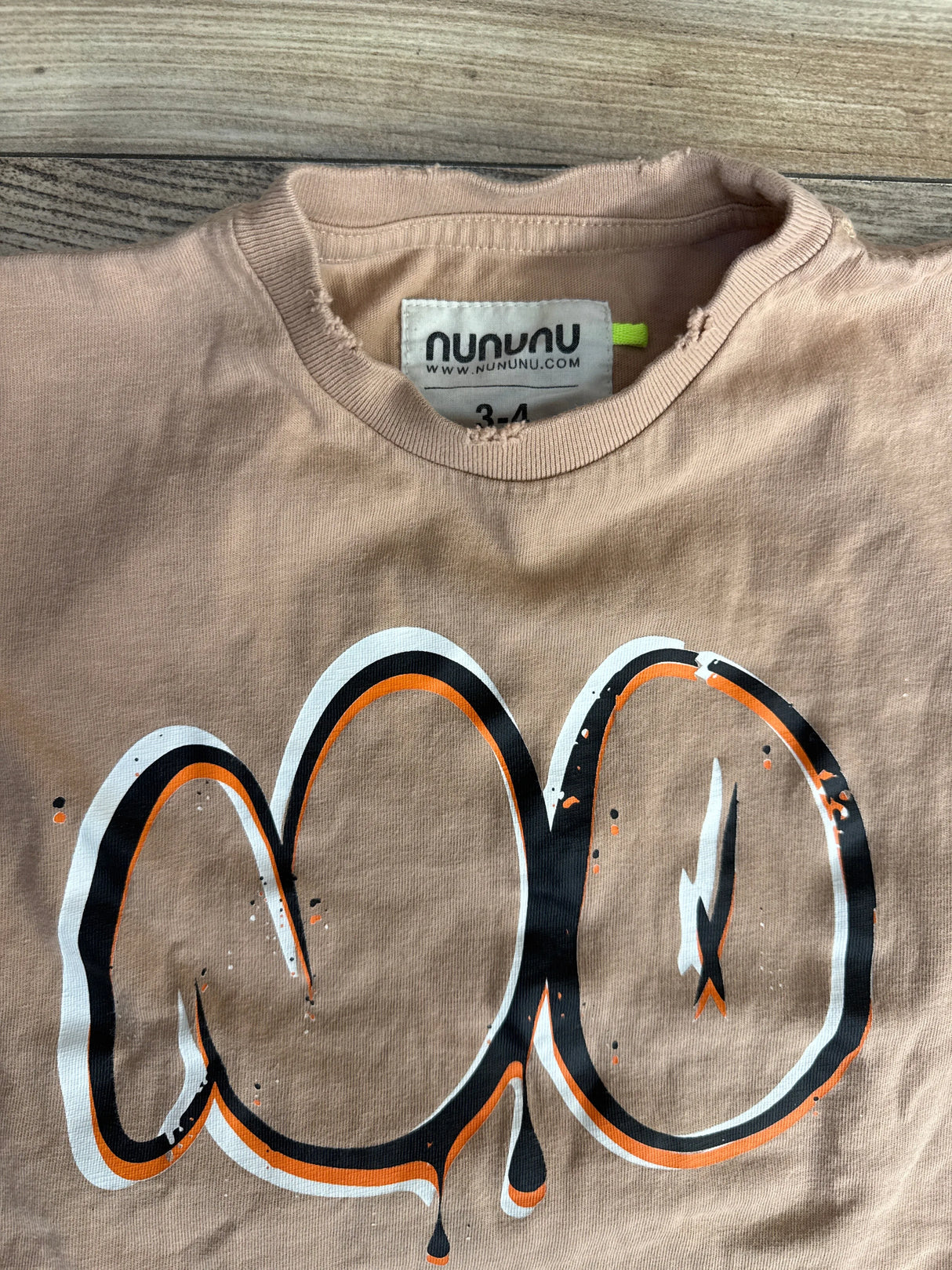 Beige toddler t-shirt with nununu brand label and bold black, white, and orange abstract graphic