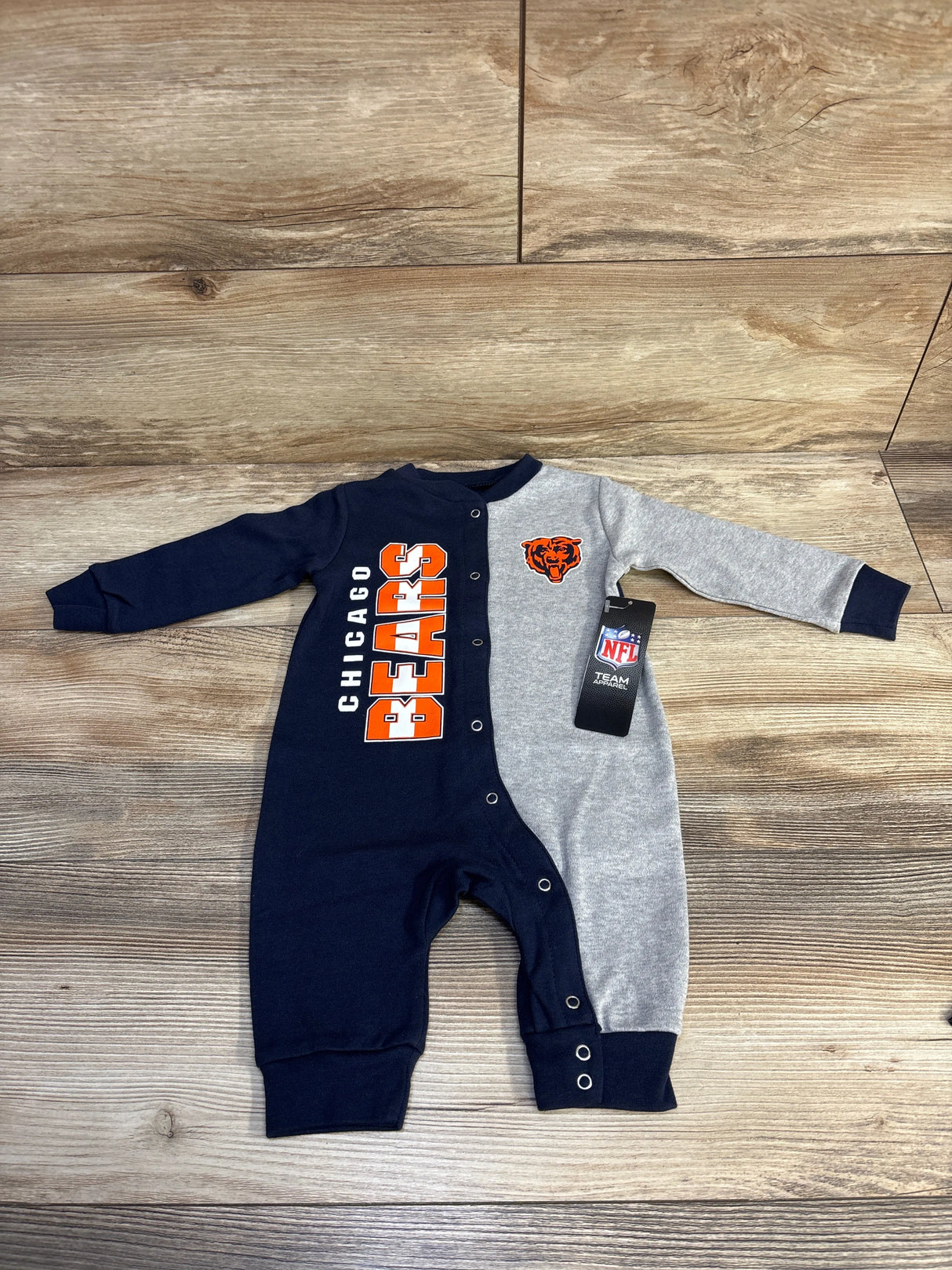 Chicago Bears baby romper with navy and gray colors, NFL team apparel on wooden floor