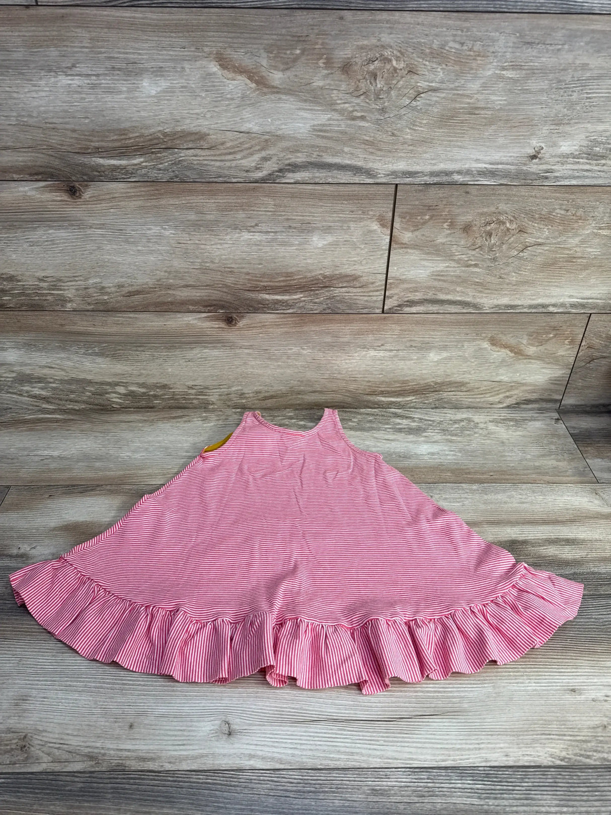 Flat lay of Petit Bateau red and white striped flare dress size 4T showcasing sleeveless top and ruffled hem on wood floor background