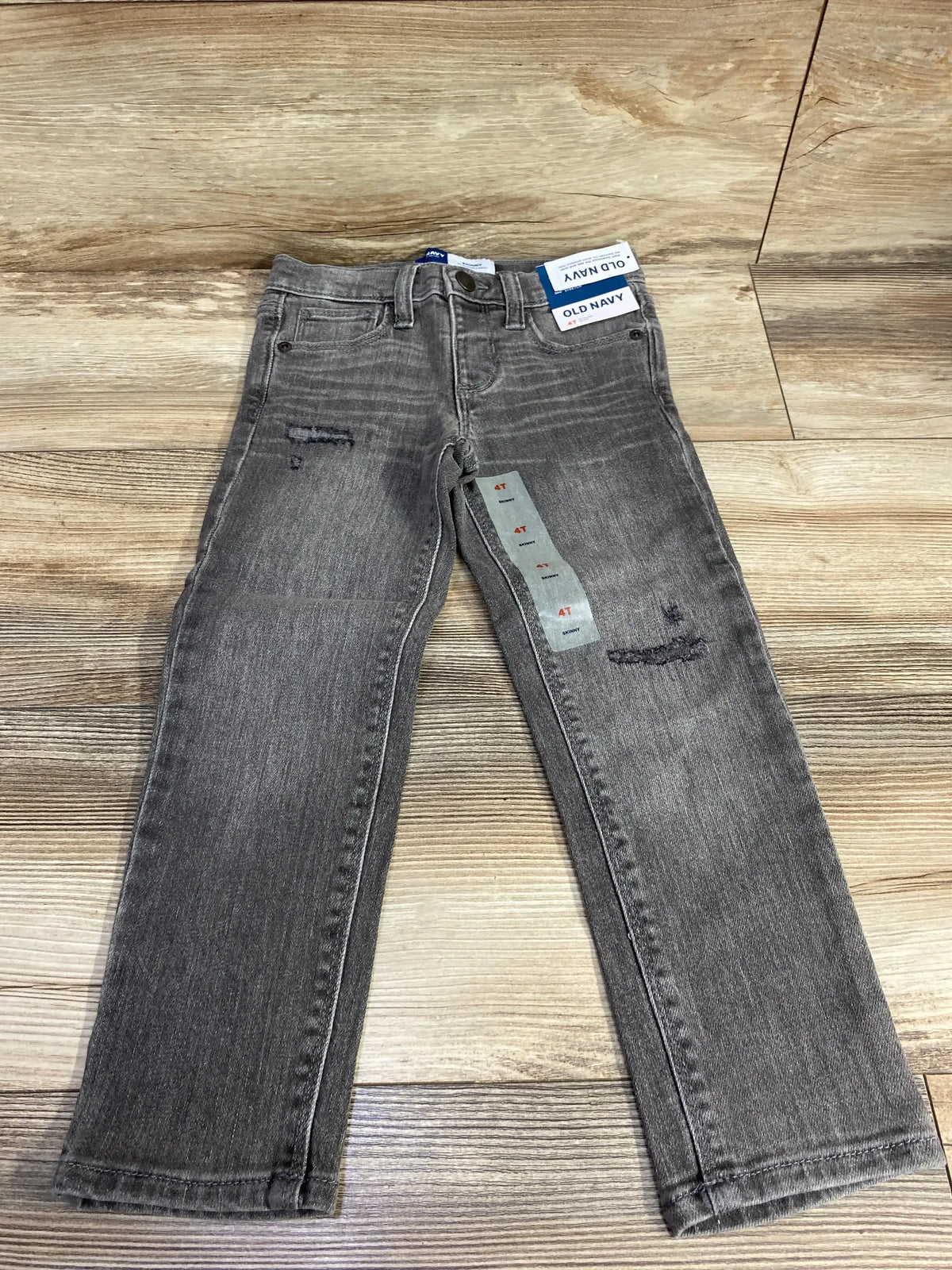 Flat lay of Old Navy 360 Stretch skinny jeans, toddler size 4T, showing front pockets and attached tags on wooden floor