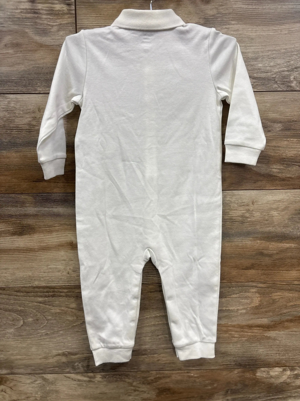 Back view of a white long sleeve baby romper on wood background