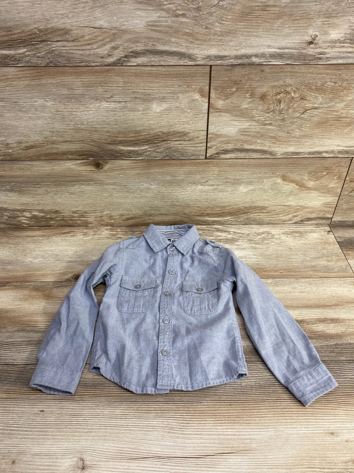 Light gray long sleeve toddler button-up shirt with chest pockets on wood background