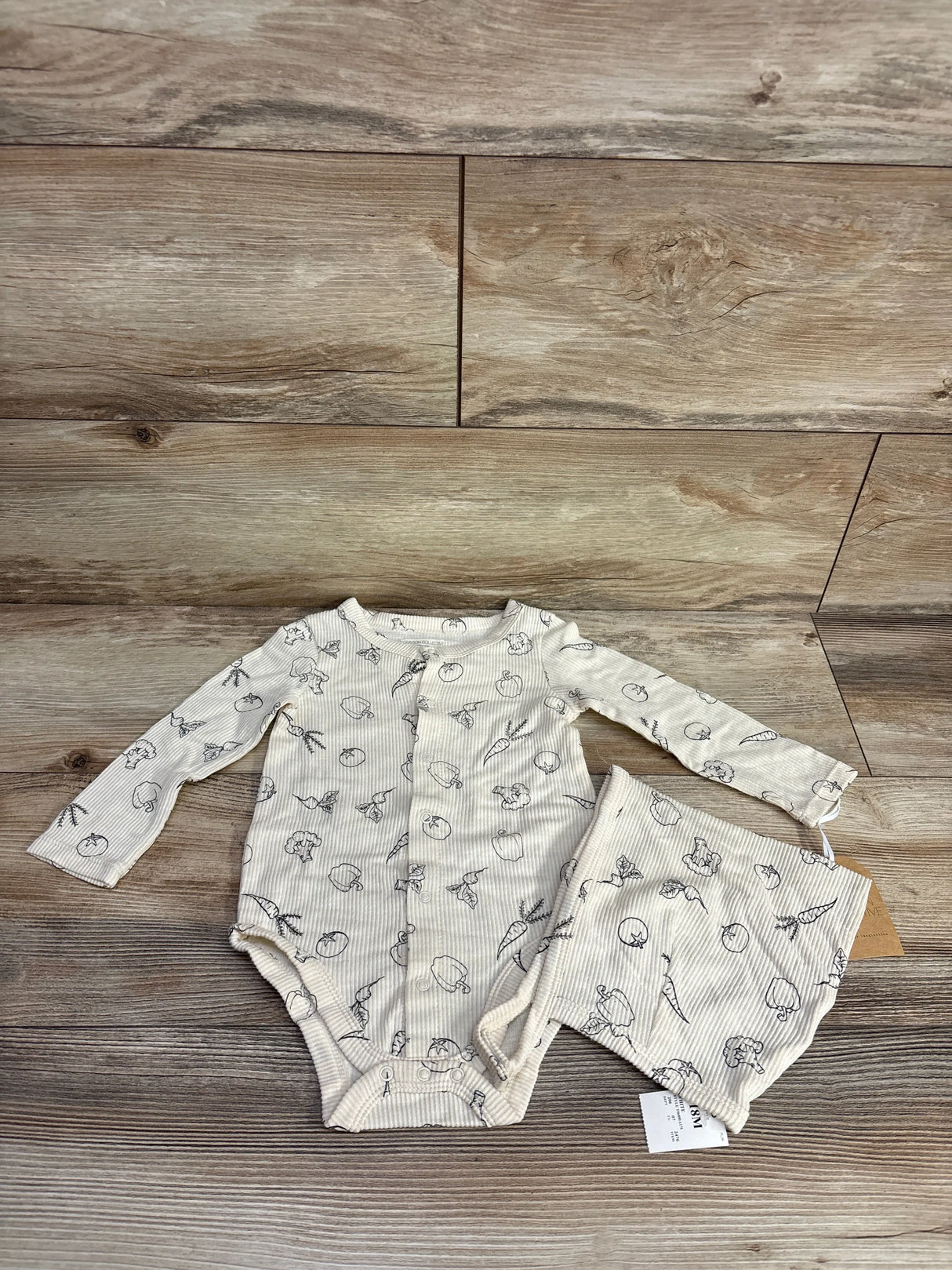 Neutral long sleeve baby bodysuit and shorts set with vegetable print on wood background