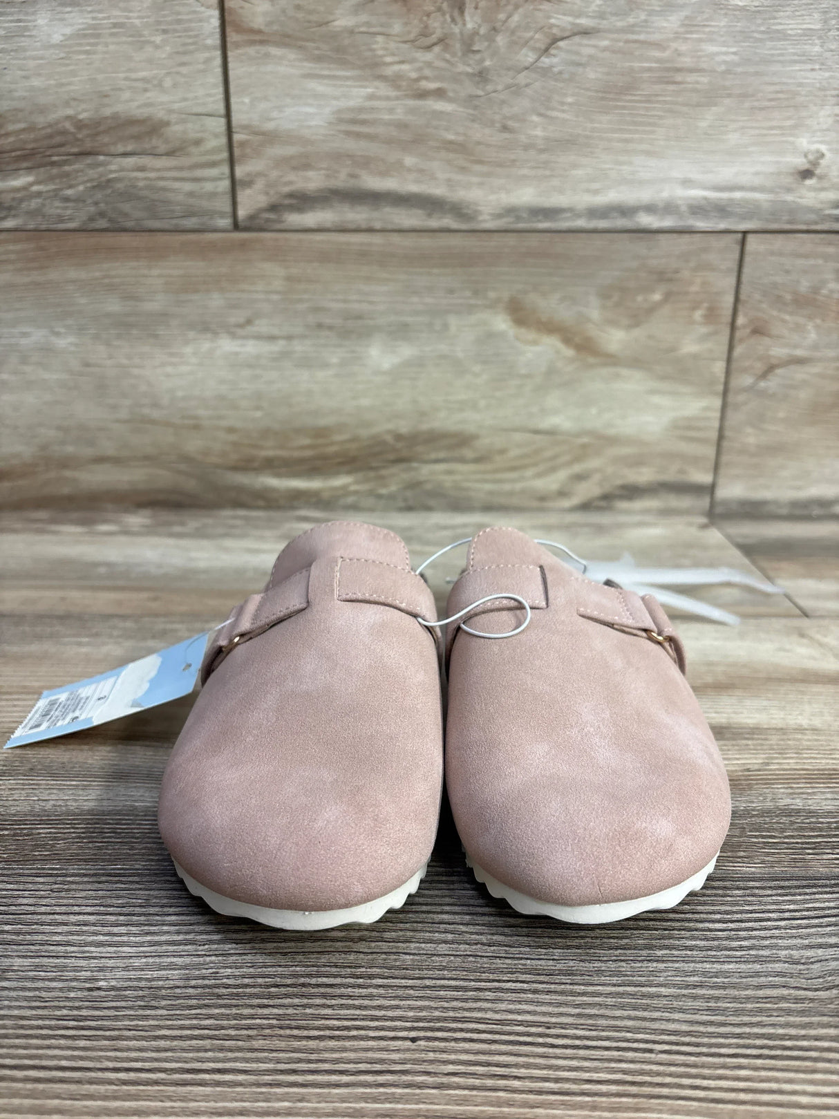 Pair of pink suede slip-on shoes with buckles, displayed on wood surface in kids resale store
