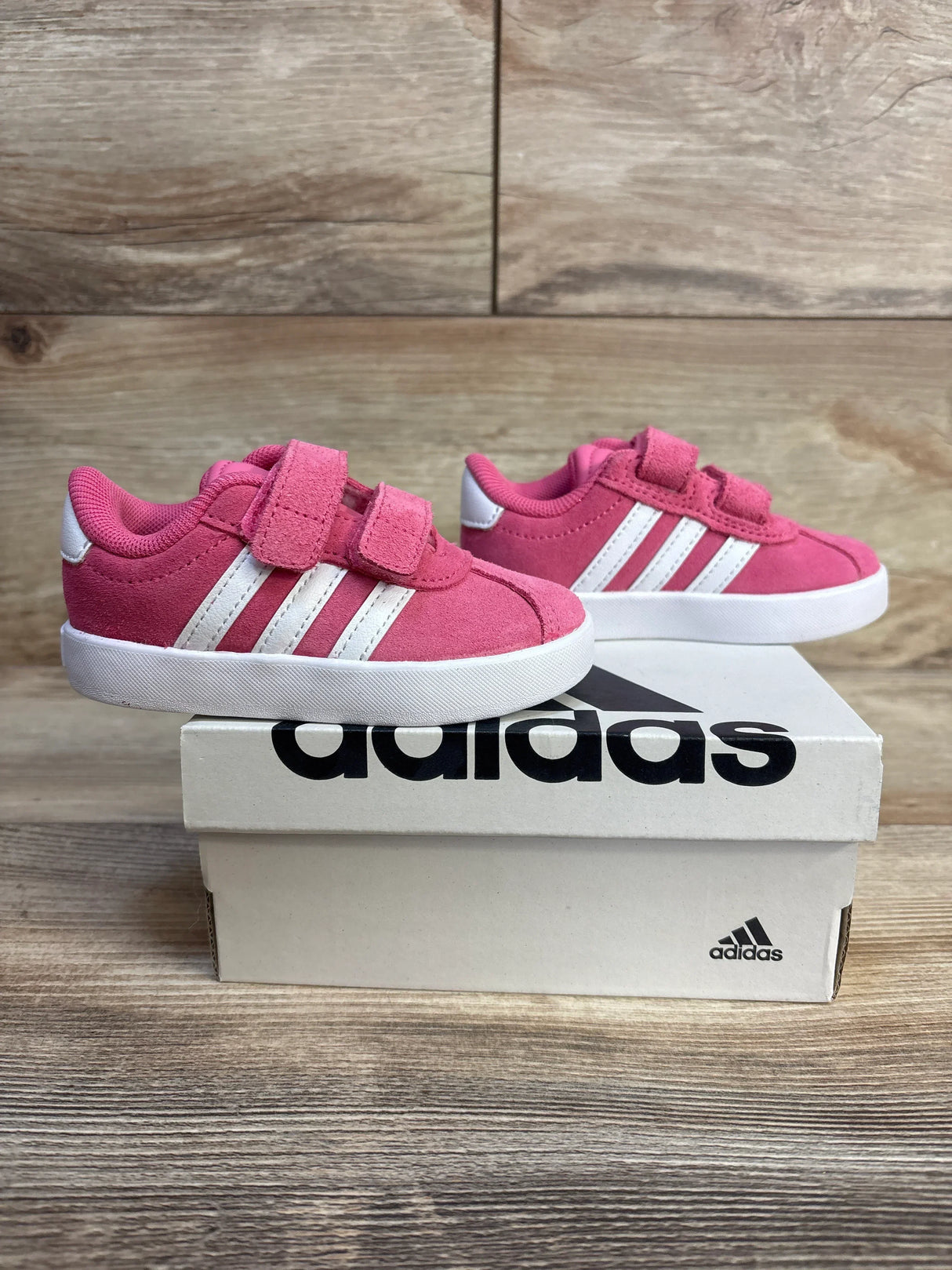 Pink Adidas toddler sneakers with velcro straps, white soles, and classic 3 stripes on box
