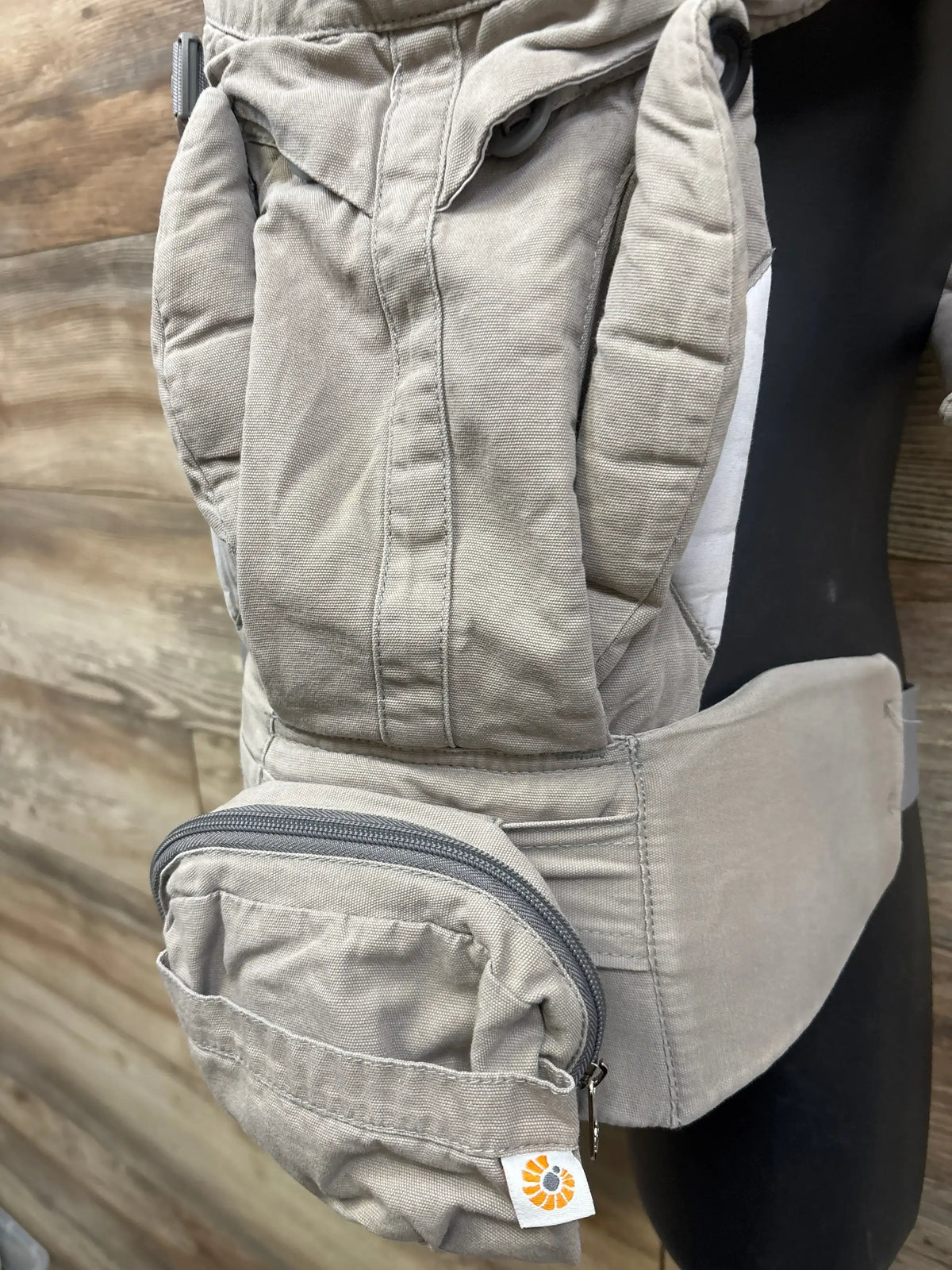 Close-up of Ergobaby Omni 360 baby carrier in pearl grey showing zippered pouch, padded straps and wide waistband on mannequin