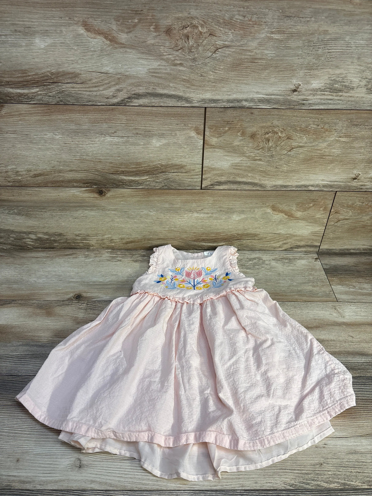 Flat lay of Max Studio pink toddler dress (4T) showing embroidered floral bodice and ruffled waist on wood background