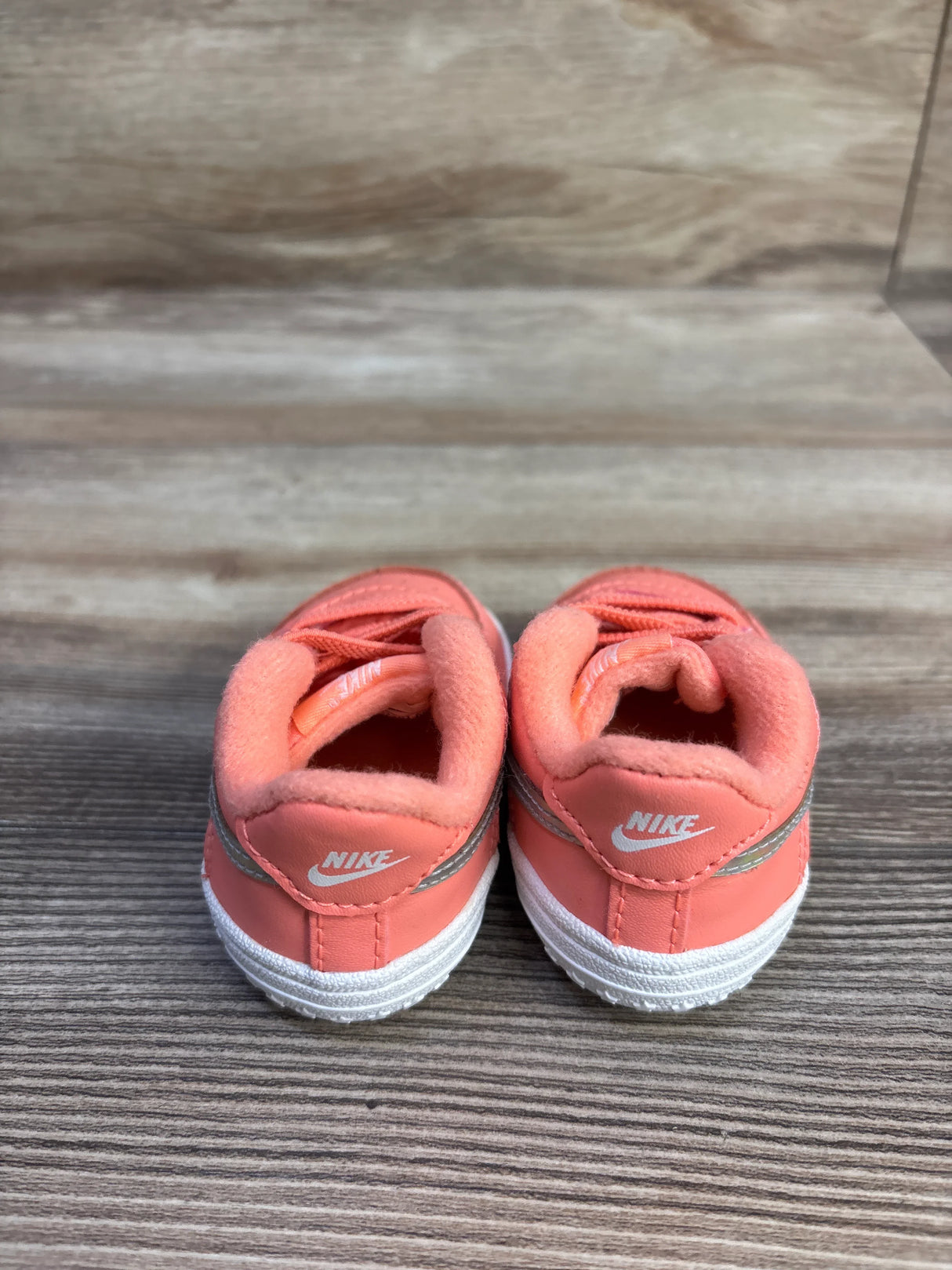 Rear view of Nike Force 1 CB sneakers size 2C in atomic pink showing white heel logos, padded collars and silver trim on wood