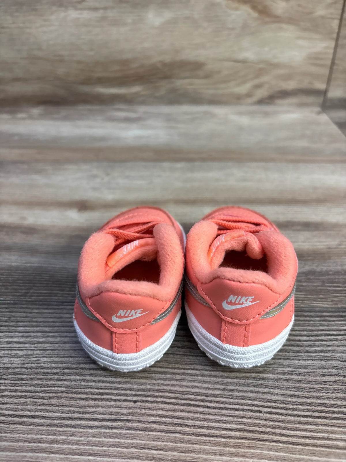 Rear view of Nike Force 1 CB sneakers size 2C in atomic pink showing white heel logos, padded collars and silver trim on wood