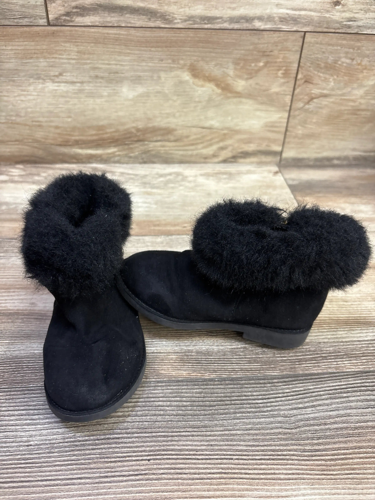 Front and side views of black Self Esteem City Girl faux-fur boots showcasing plush collars on a wood-look floor