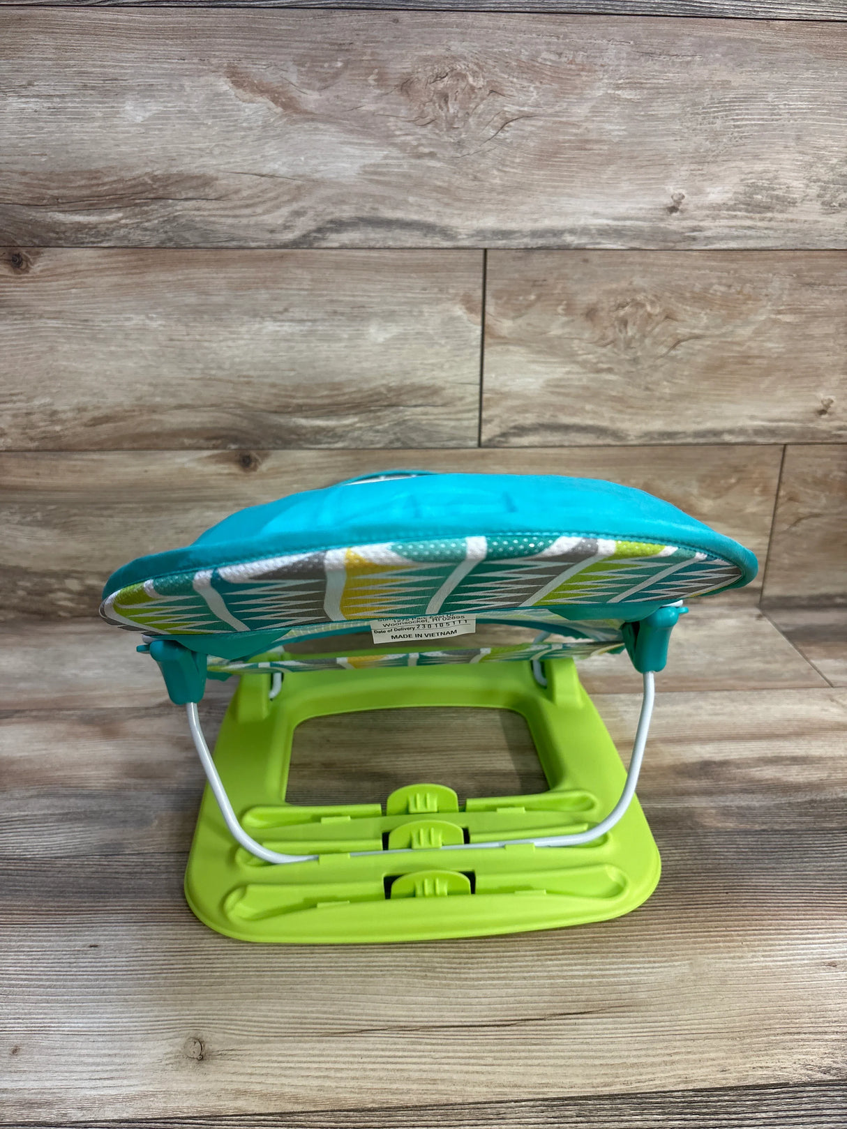 Green and blue baby bouncer seat on wood floor, gently used kids gear