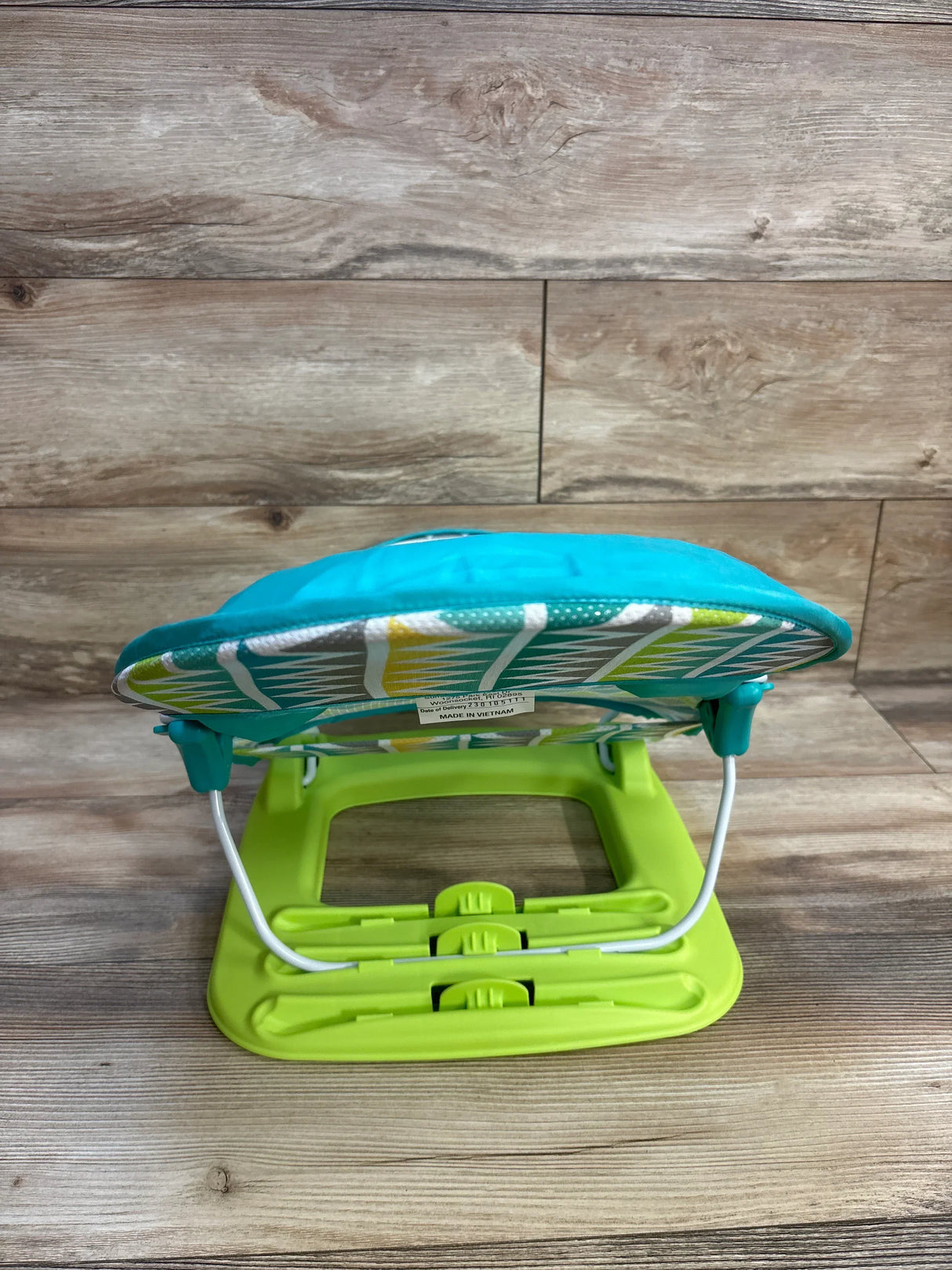 Rear view of Summer Deluxe Baby Bather in green and turquoise showcasing adjustable three-position base on wood floor