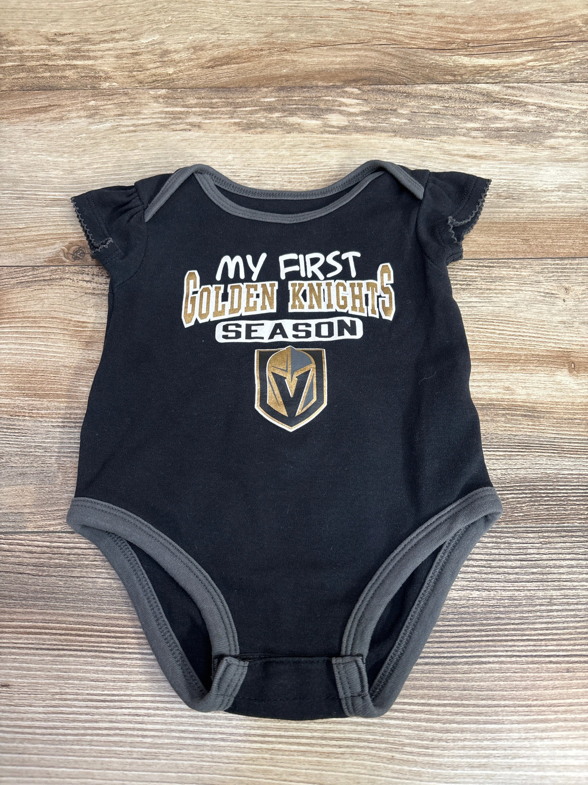 Black baby onesie with gray trim featuring Vegas Golden Knights logo and text My First Golden Knights Season