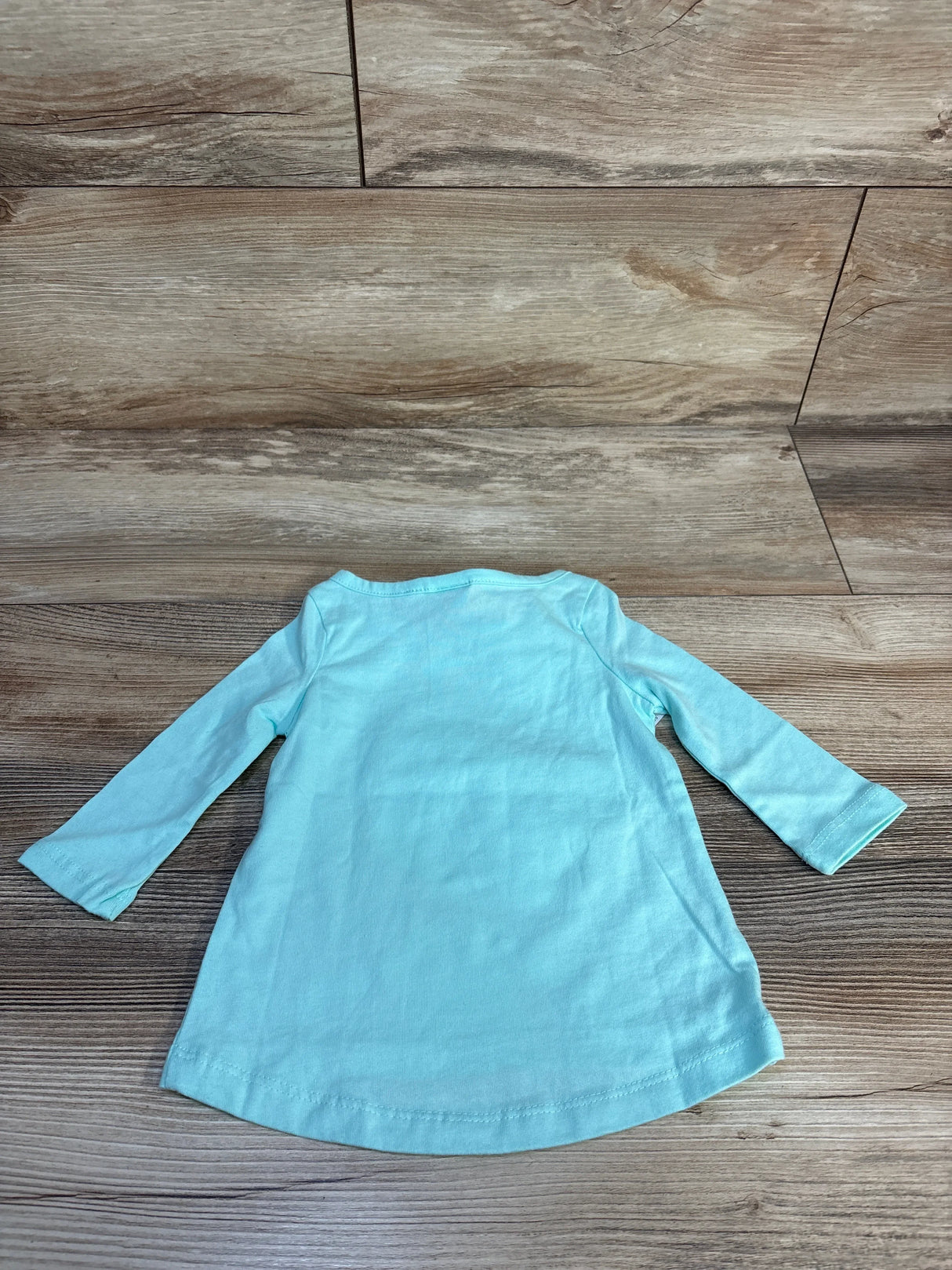 Light blue long sleeve baby dress on wood background, gently used children's clothing