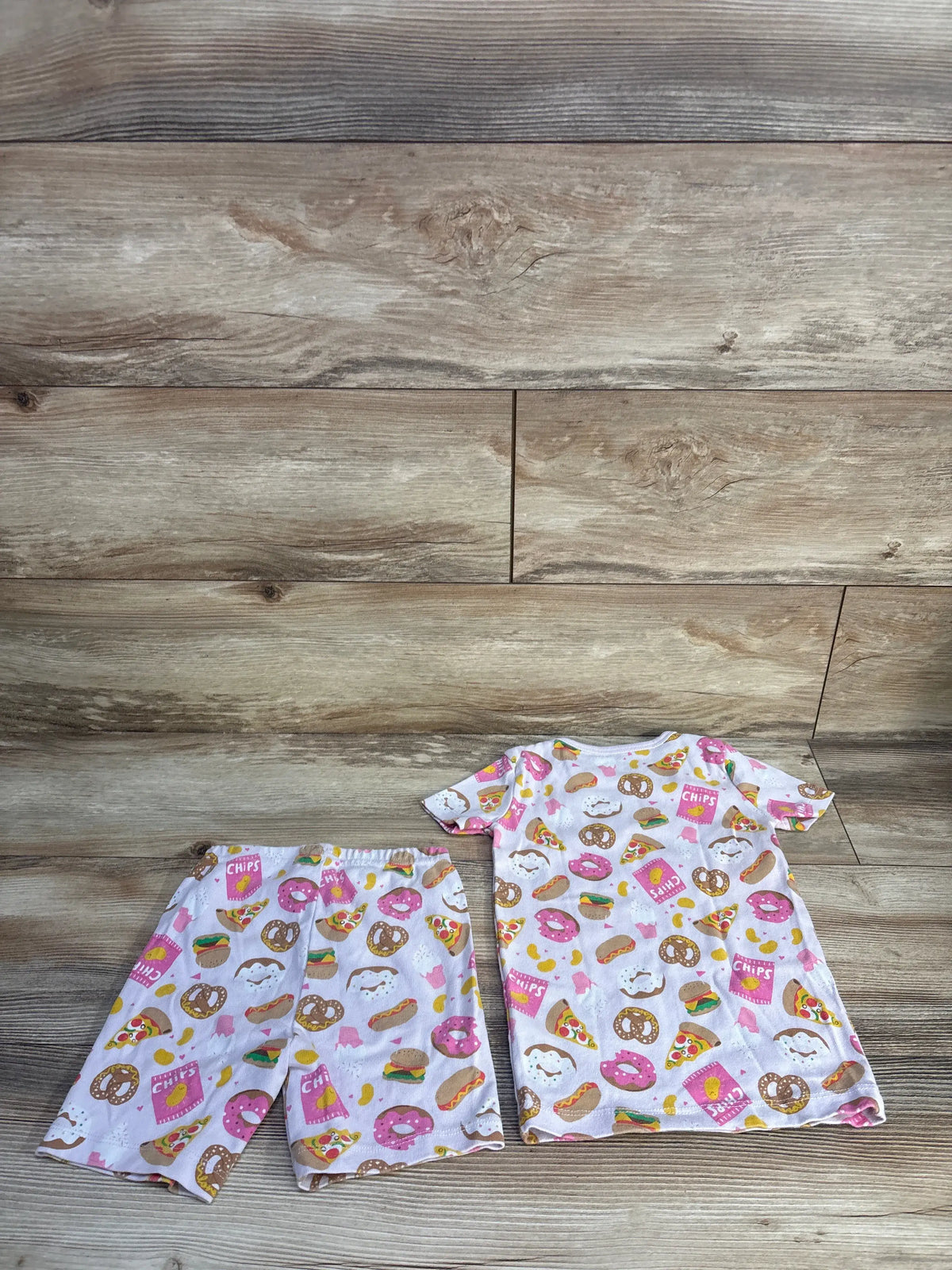 Front view of Janie & Jack 2-piece short pajama set in pink with snack print on wood flooring